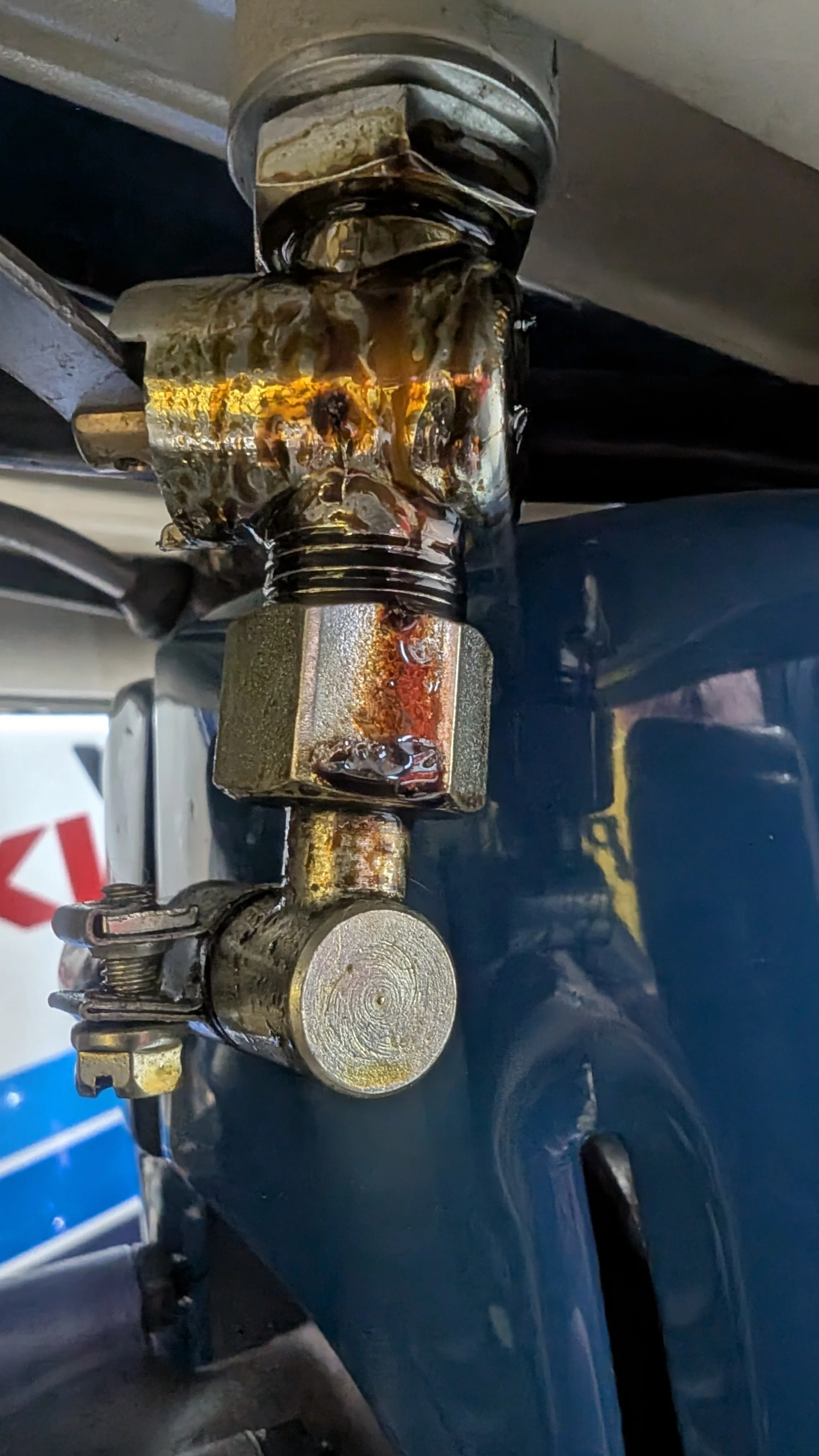 Close-up image of a metal mechanical joint or connection with visible oil, rust, and wear.