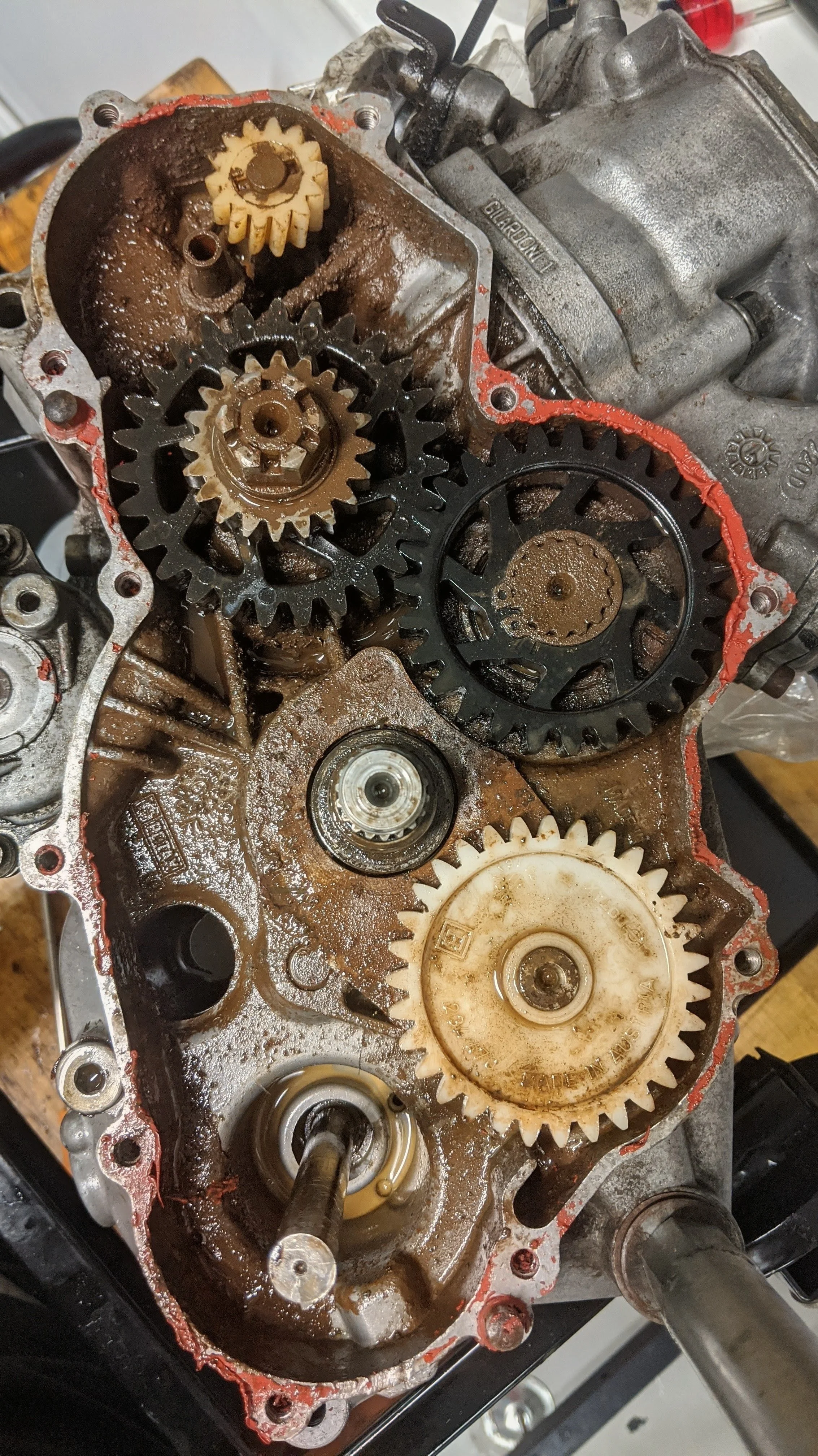 Close-up view of the inside of a disassembled mechanical device, showing gears and oil inside a metal casing with a gasket seal.