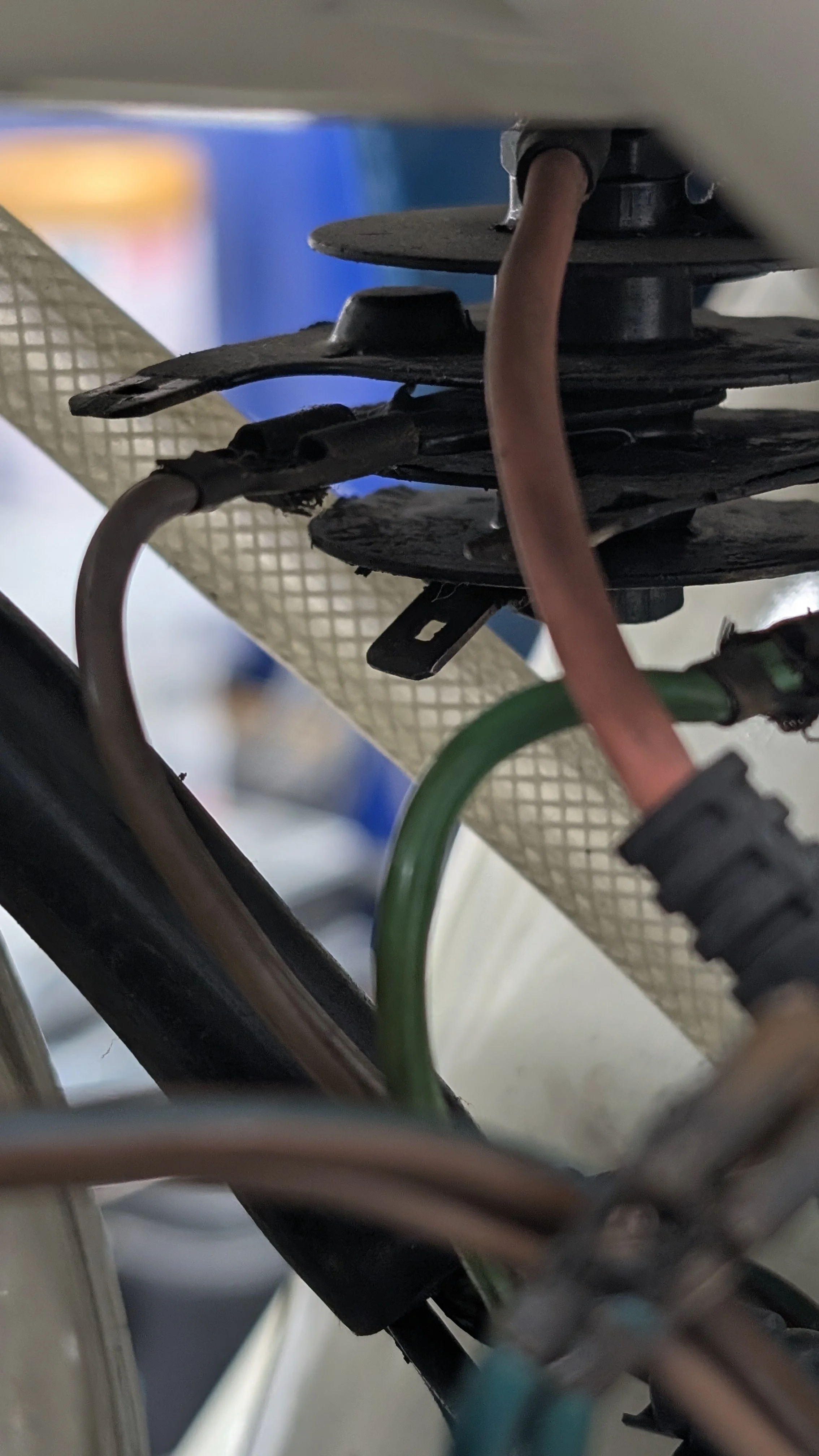 Close-up of electrical wires and components under a product or device, with some wires connected to terminals and others hanging loosely.