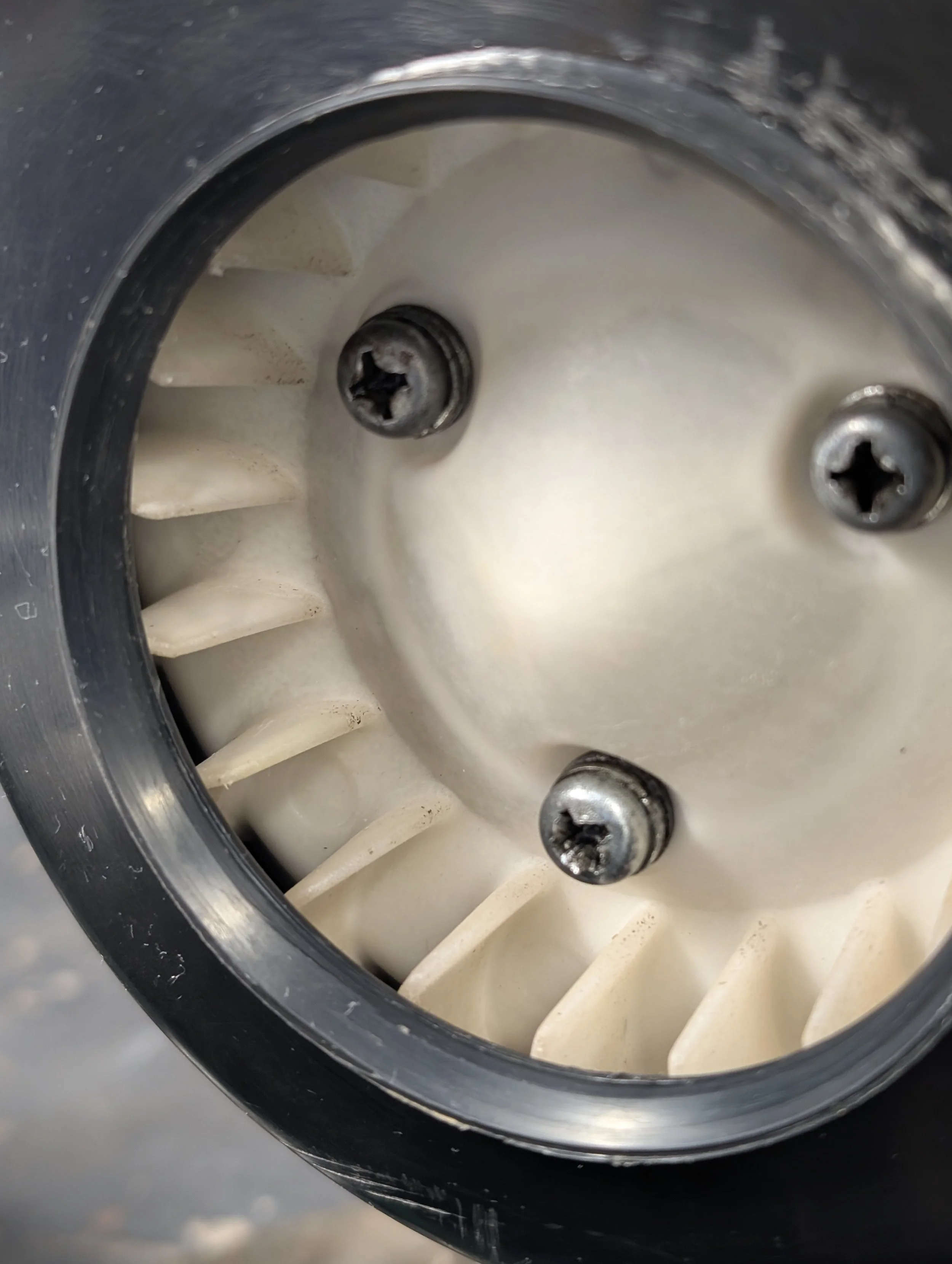 Close-up of the interior of a piece of industrial or mechanical equipment showing several screws and a comb-like structure inside.