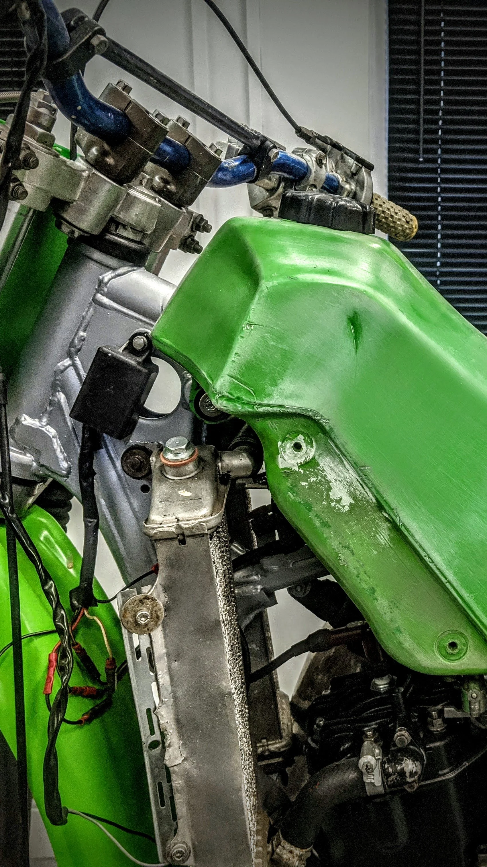 Close-up of a motorcycle frame with a green fairing, exposing parts like the radiator, wiring, and engine components.