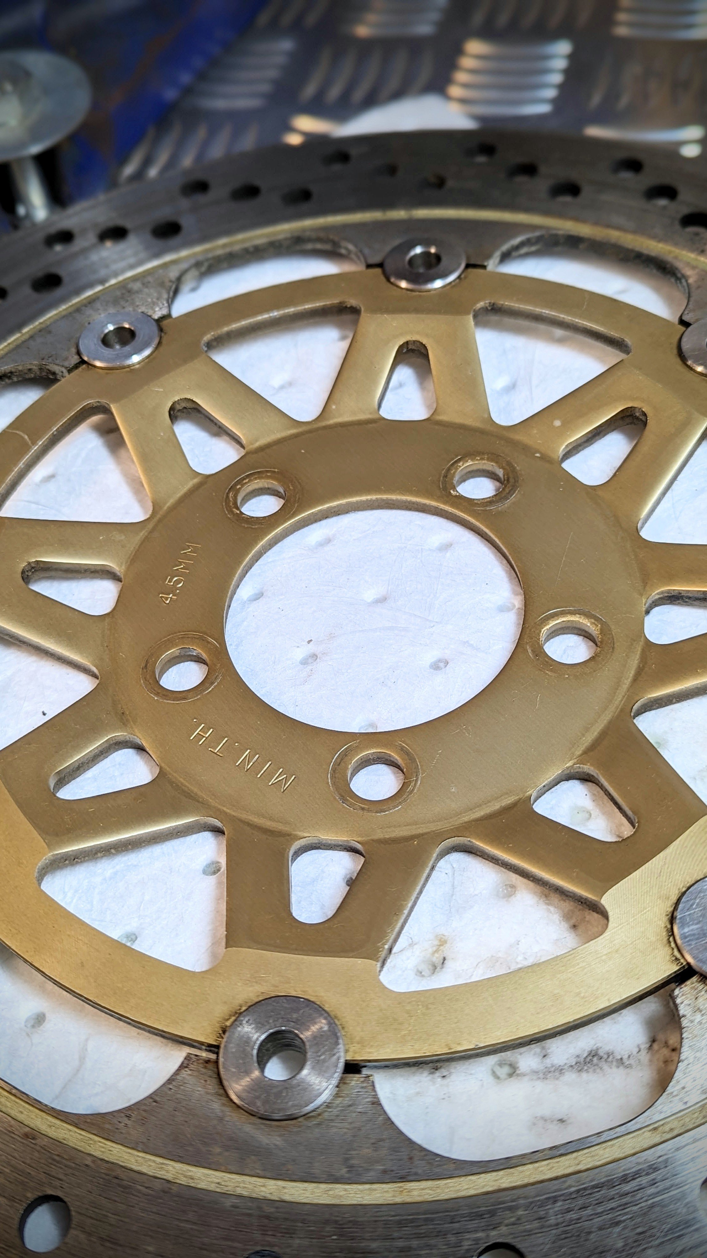 Close-up of a motorcycle sprocket with a gold-colored chain wheel and other metal components.
