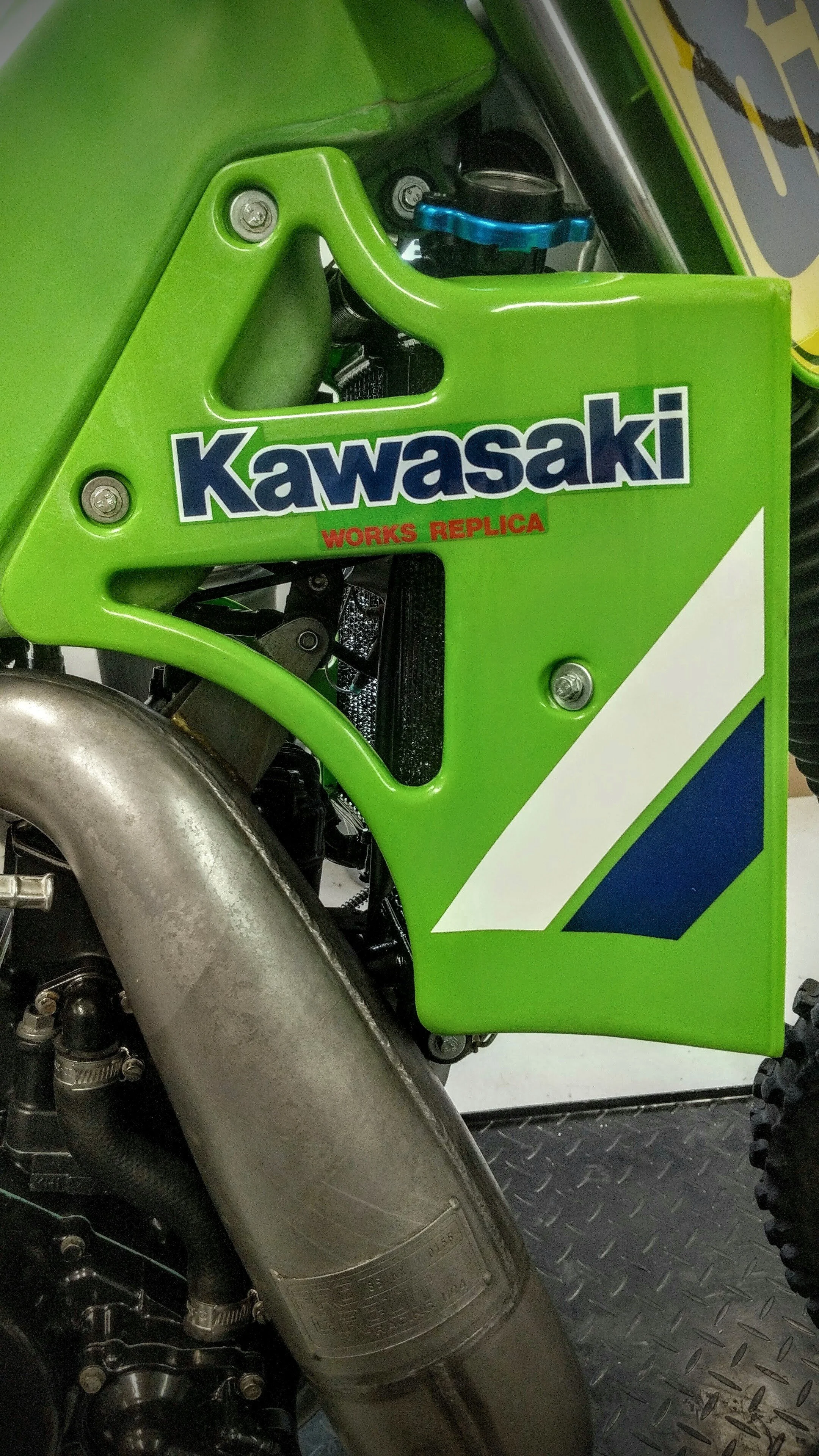 Close-up of a green Kawasaki motorcycle with a silver exhaust pipe and black engine components.