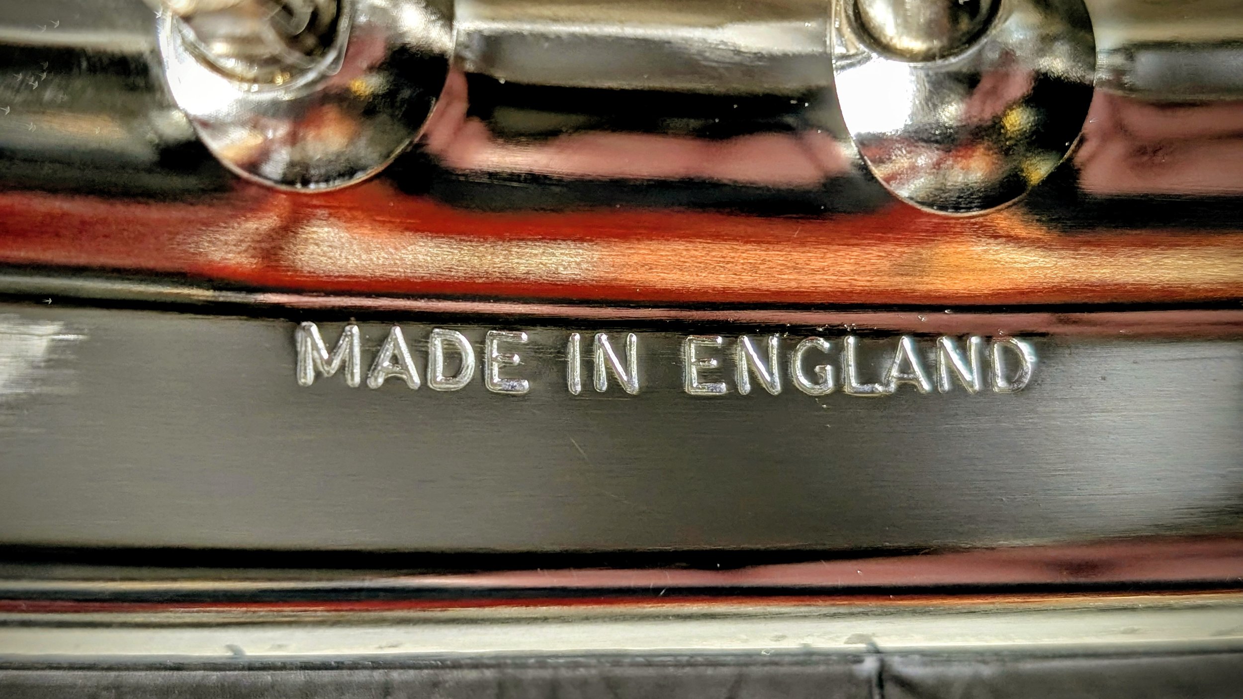 Close-up of a metal surface with the engraved text 'Made in England' and part of a metallic component with screws. Restoration Triumph, classis British bike English chrome rims with stainless steel spokes. Barn find Triumph T100 restoration project. 