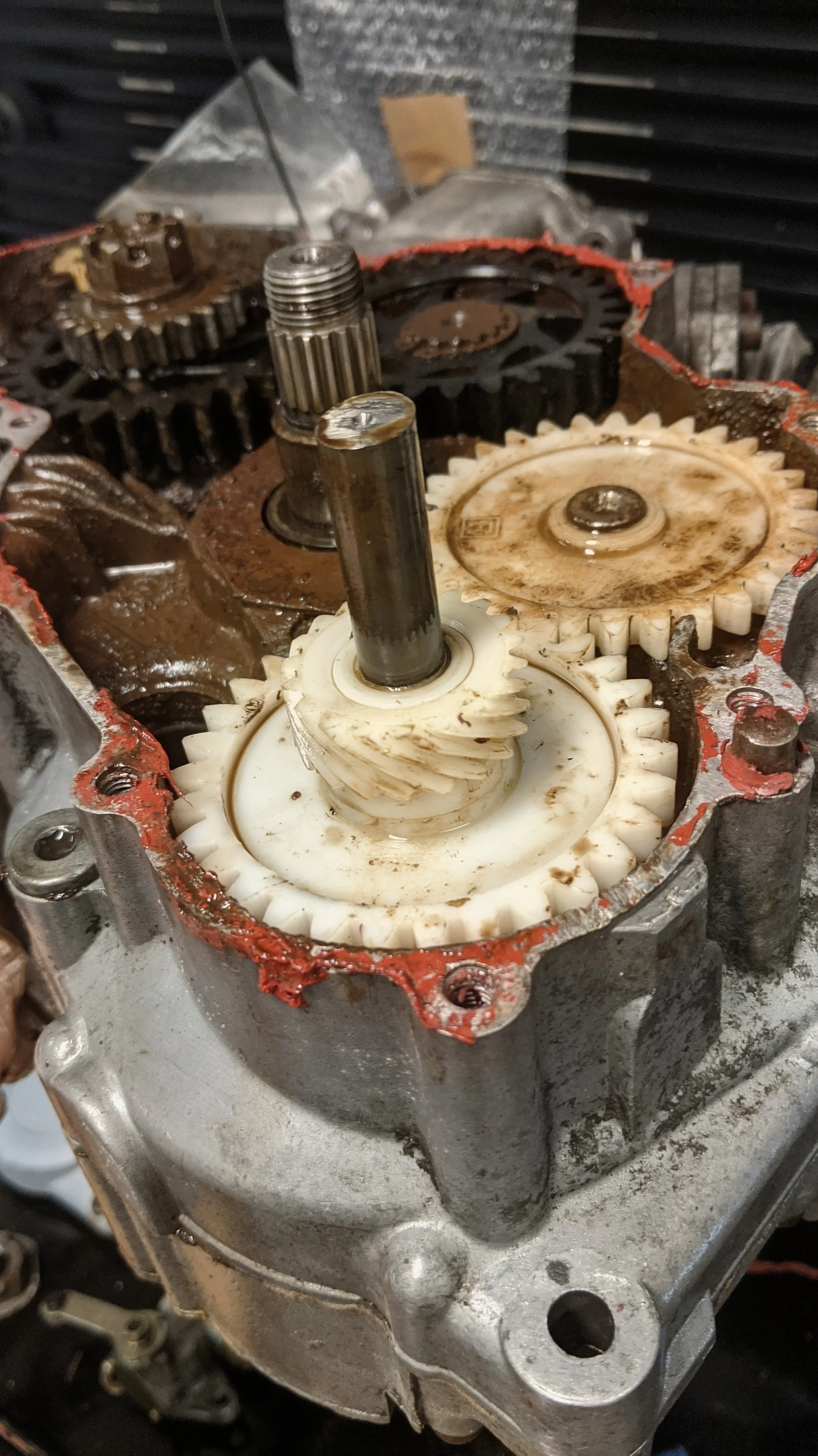 Close-up of a mechanical gear system with gears, shafts, and lubricants inside an engine or machinery housing.