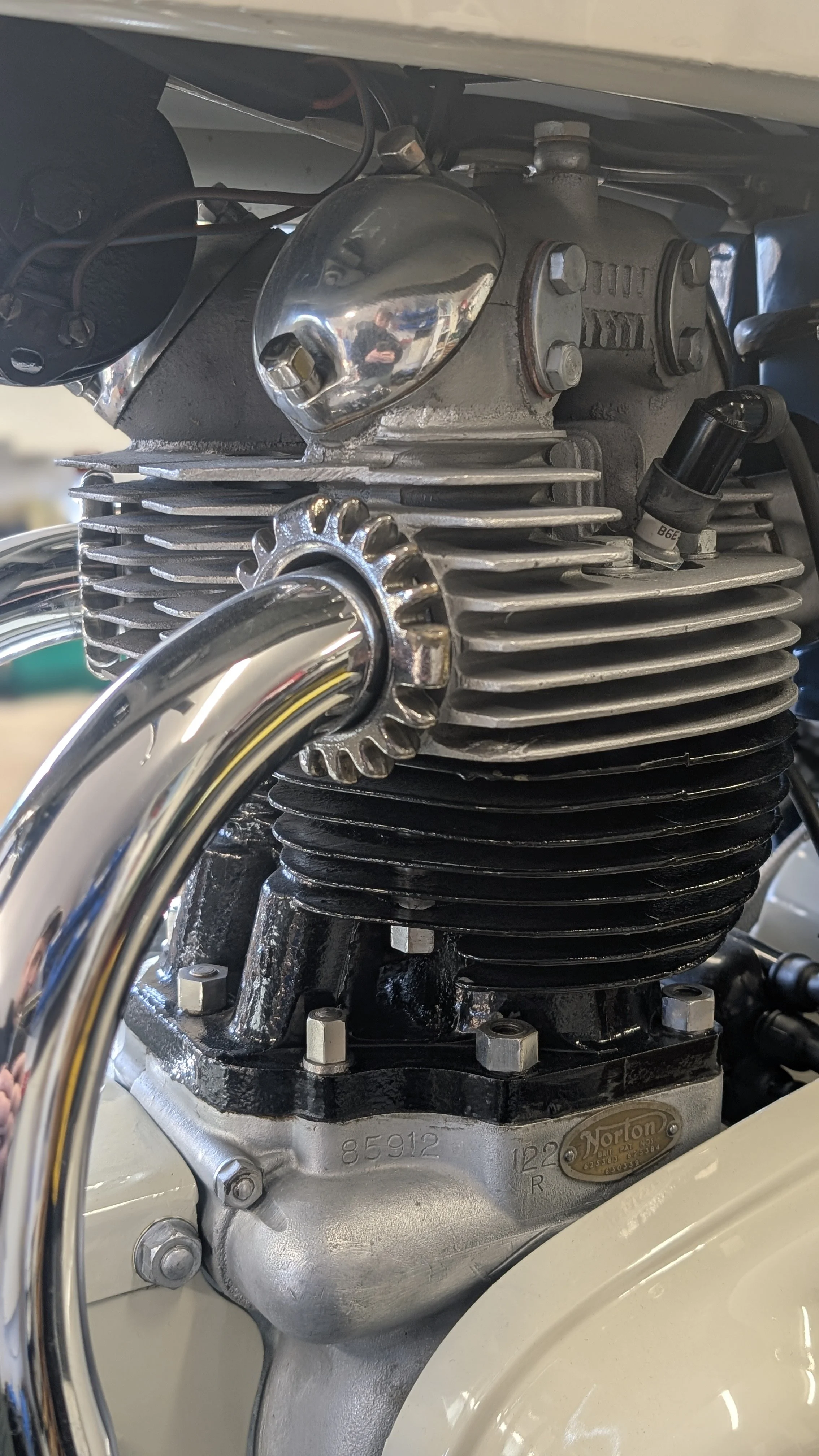 Close-up of a vintage motorcycle engine showing cylinders, cooling fins, and chrome exhaust pipes.