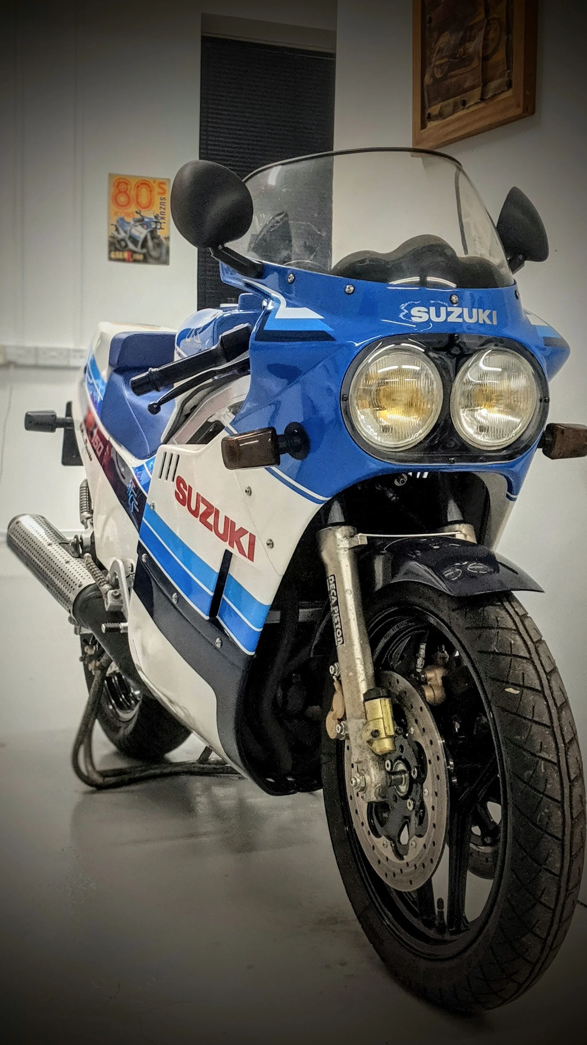 A vintage Suzuki GSX-R motorcycle with blue, white, and red racing stripes, parked indoors.