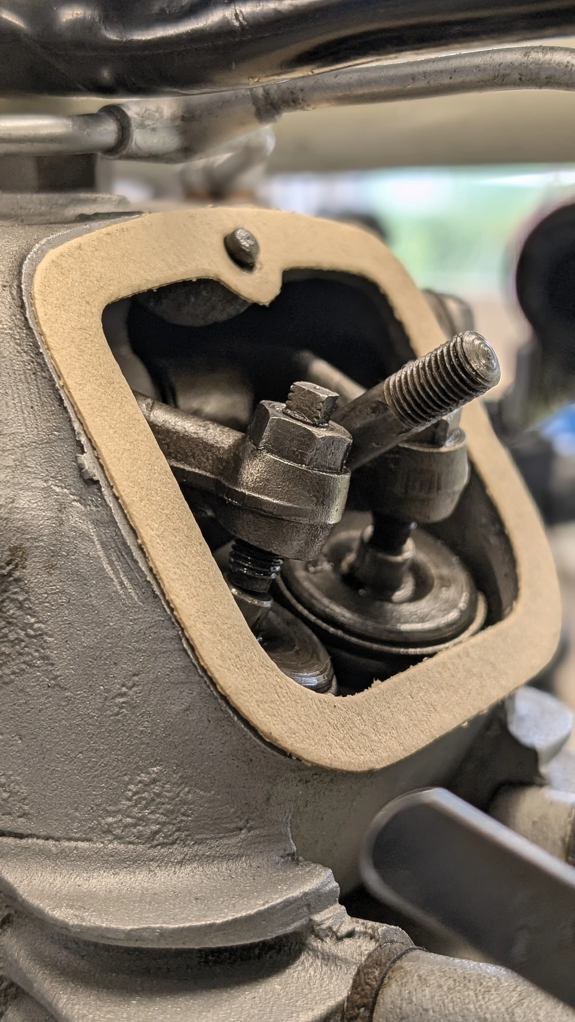Close-up of engine valve components, including a valve stem, spring, and rocker arm, inside a mechanical engine engine section.