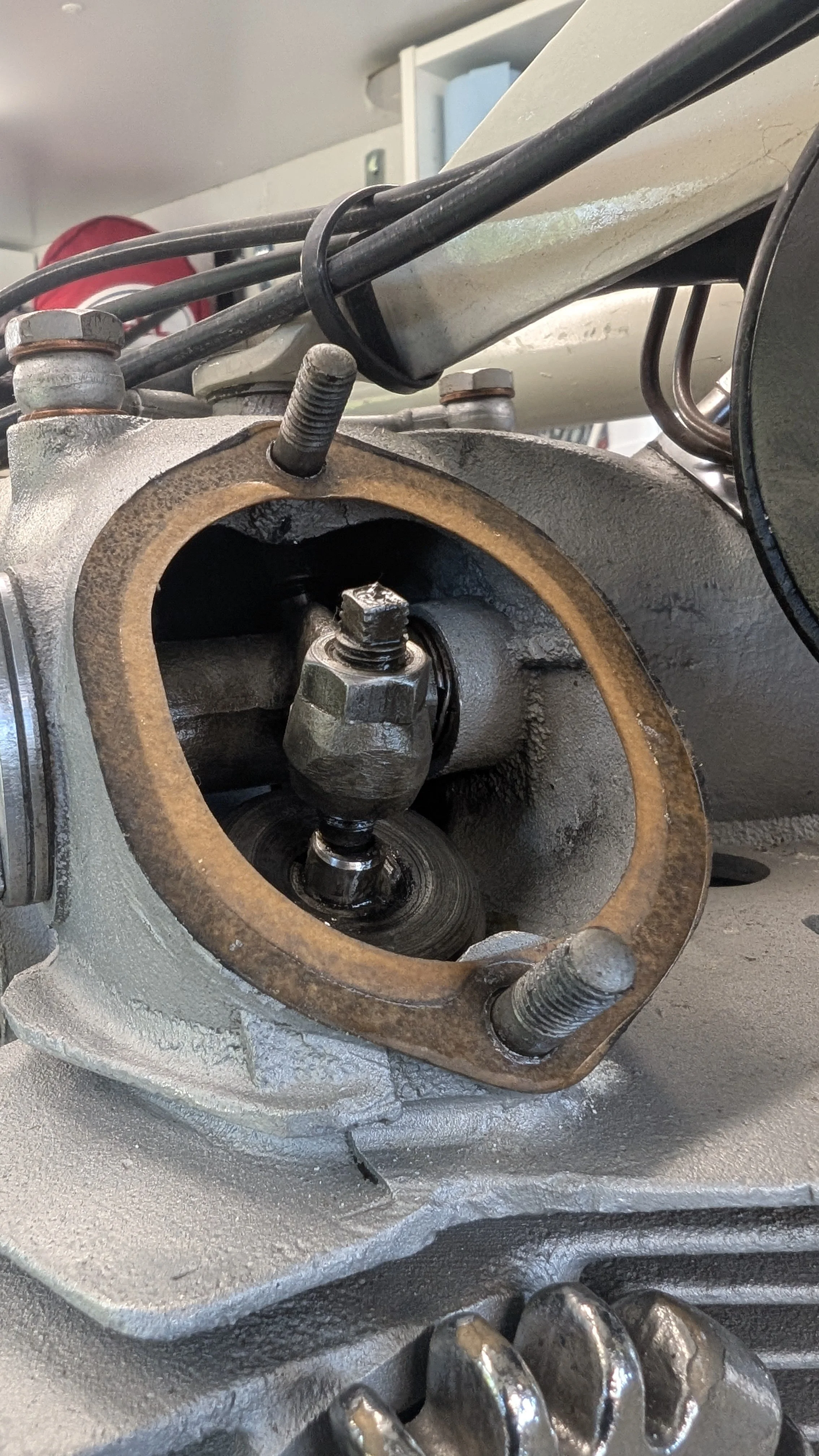 Close-up of a disassembled engine cylinder head with valve components and bolt, in a workshop setting.
