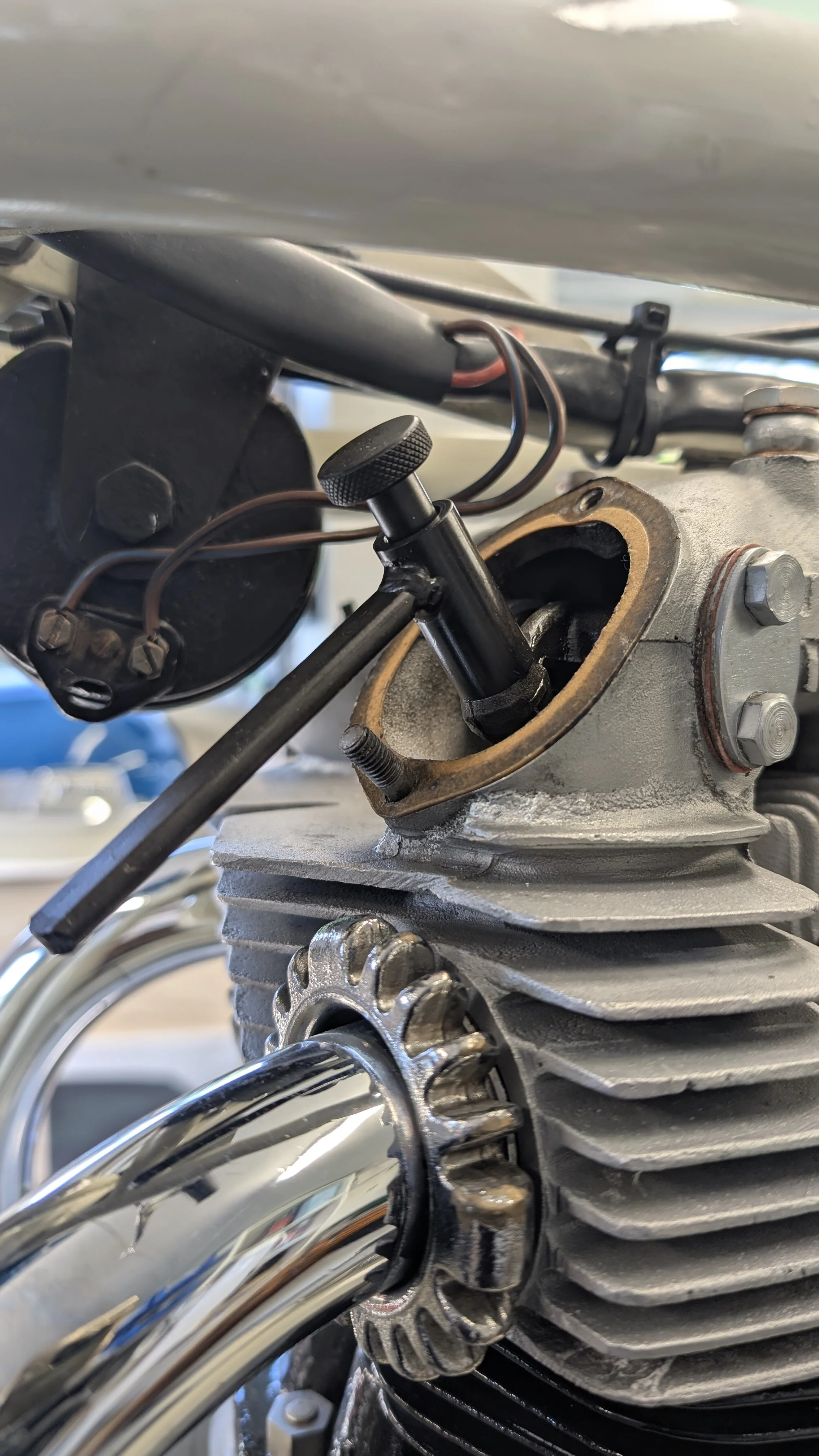 Close-up of a motorcycle engine with a removed spark plug, showing the cylinder head and spark plug socket.