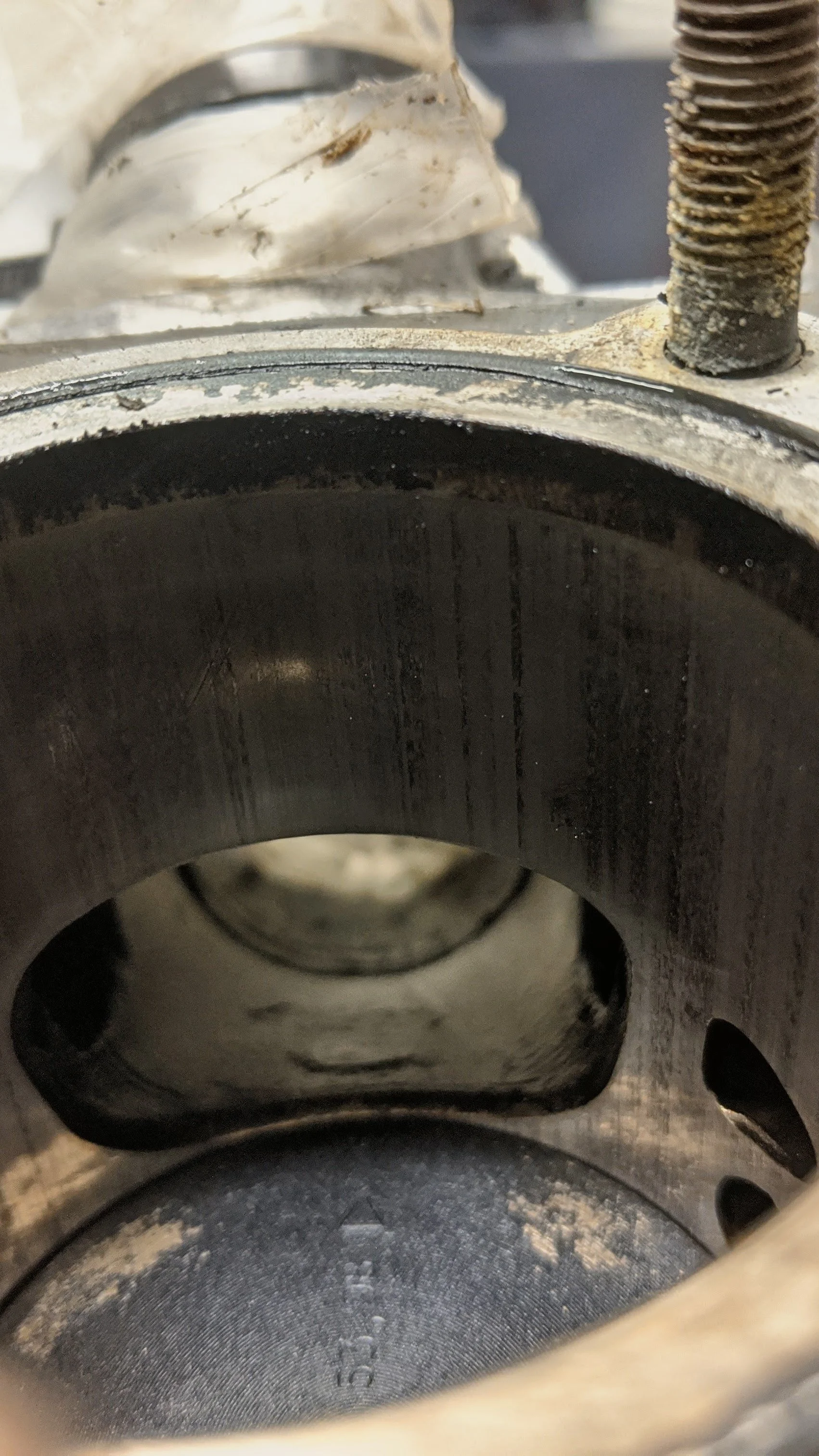 Close-up of a worn piston with a dark, smooth interior. Visible piston ring groove at the top and rim with some dirt and grime.