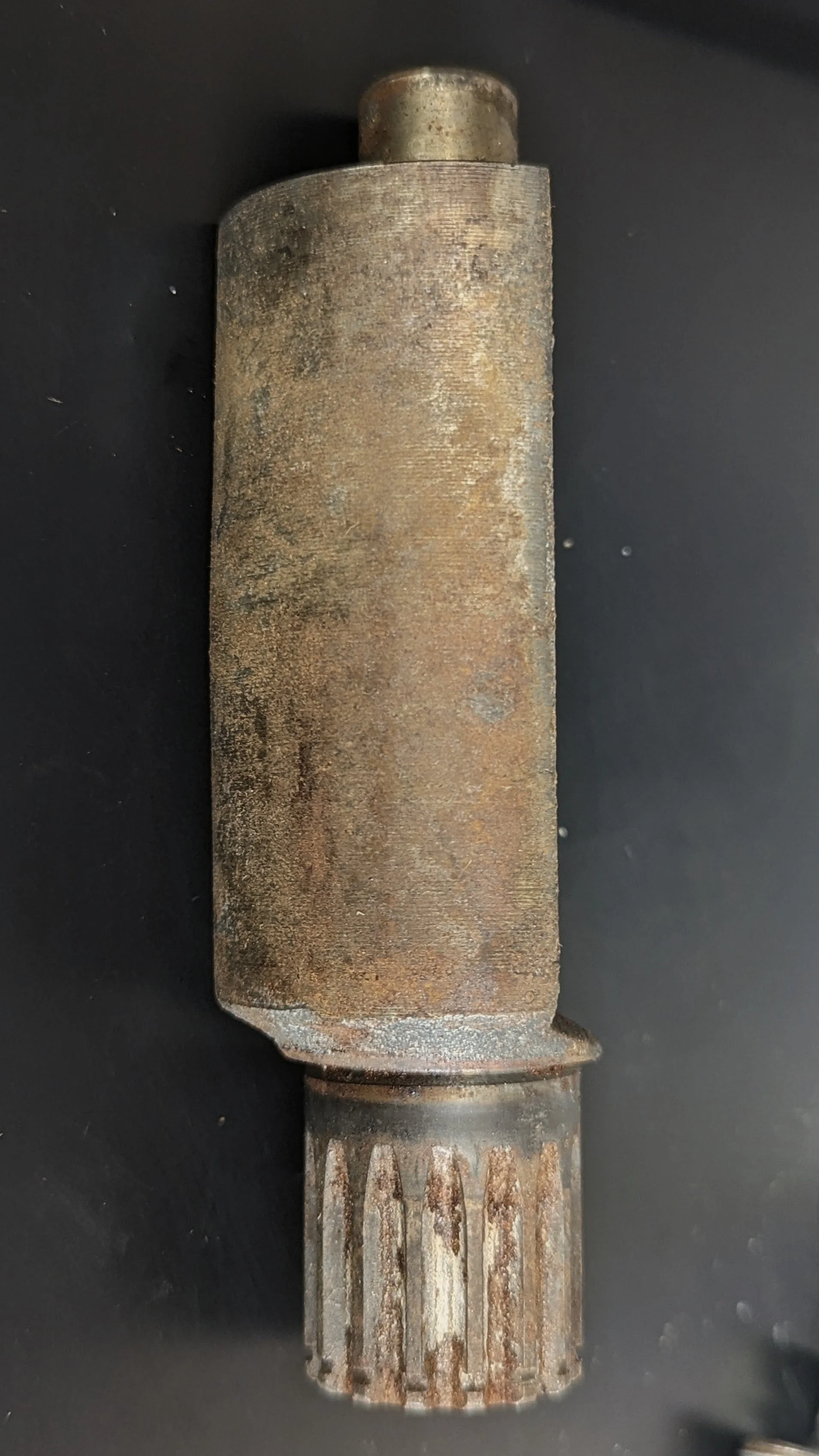 Close-up of a rusty, old metal component, possibly a gear or mechanical part, against a black background.