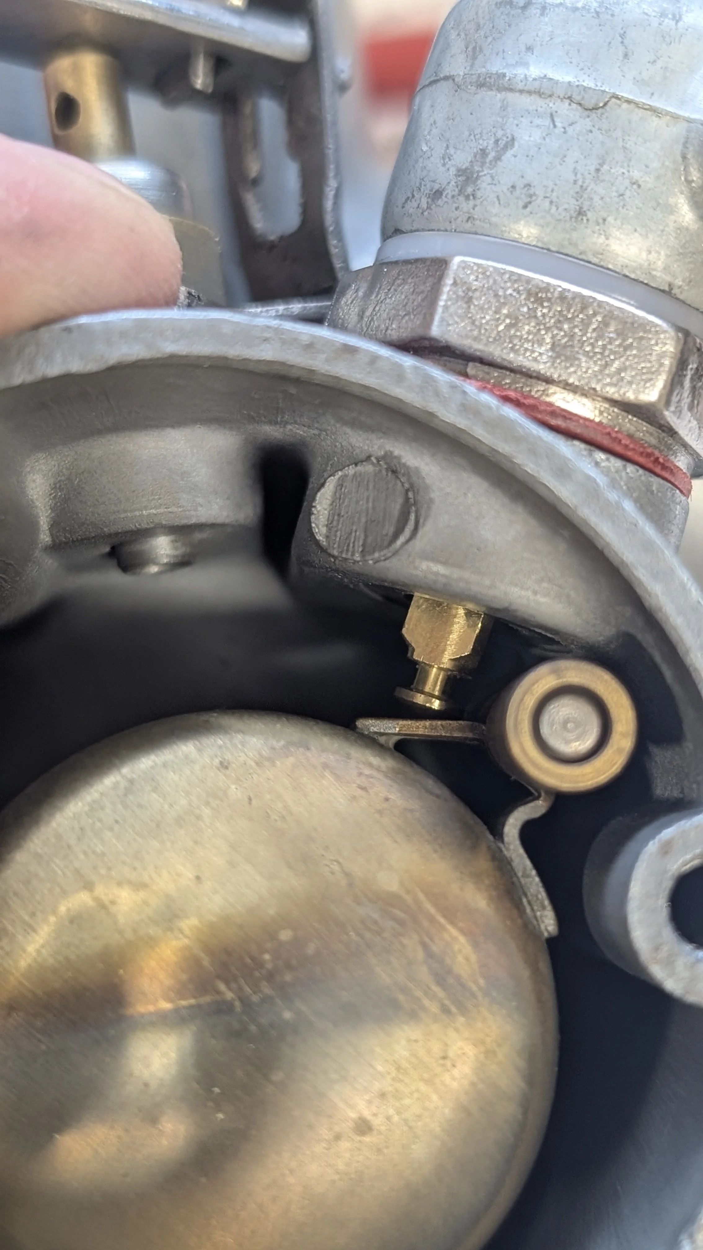 Close-up of metallic engine parts with a person's finger near the component.