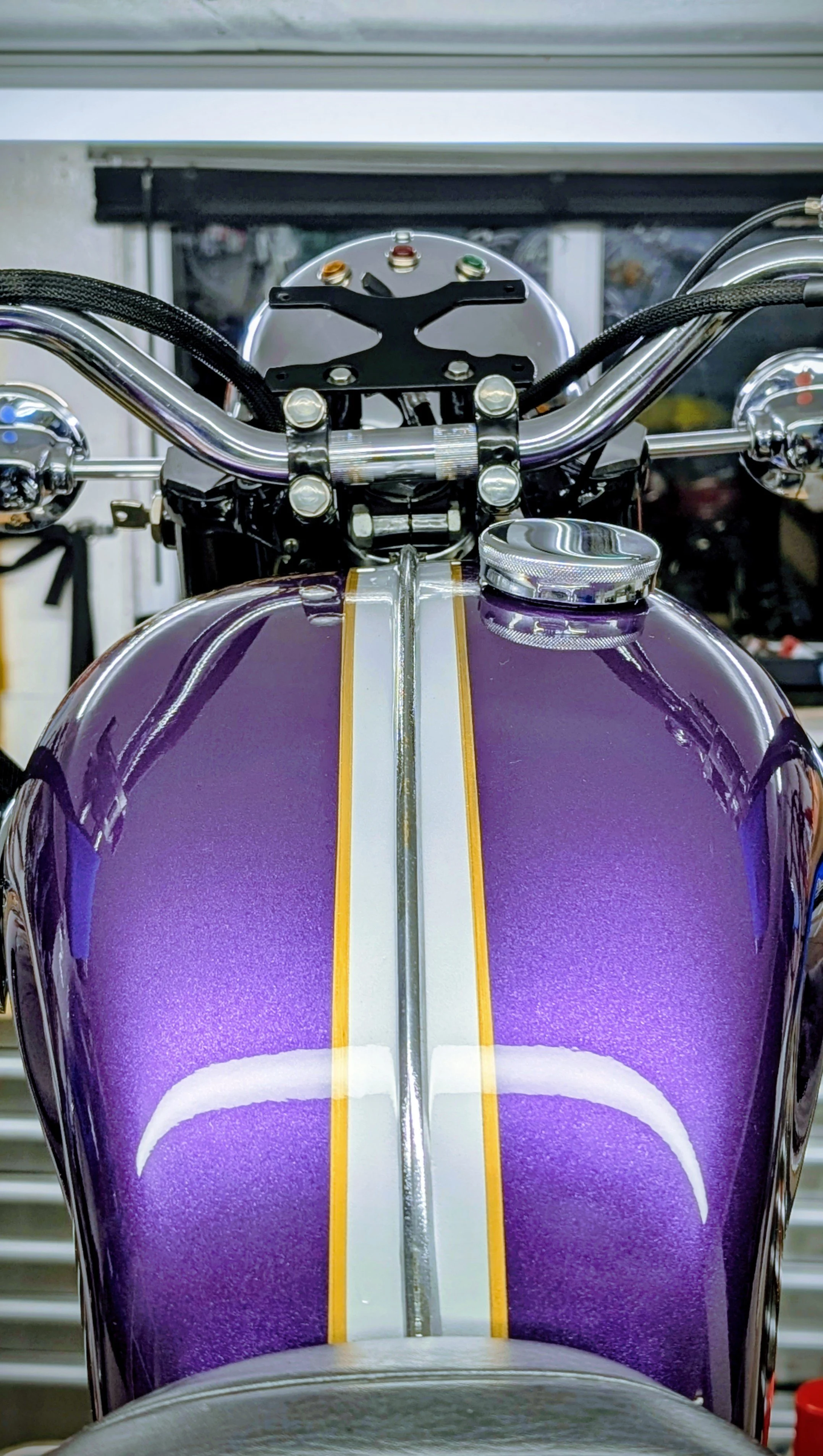 Close-up of a purple motorcycle fuel tank with grey and gold pinstriping. Vintage Triumph original colours. Barn find Triumph T100 restoration project. 