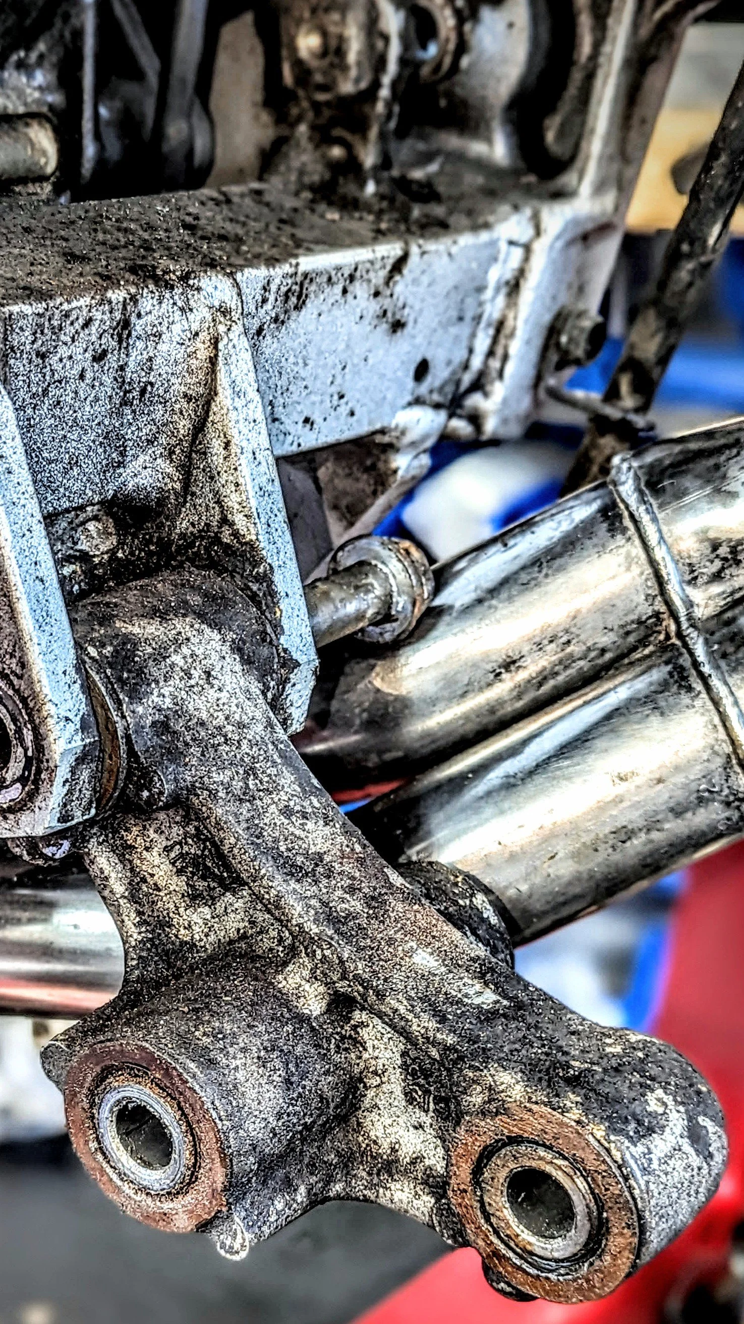 Close-up of a dirty and worn metal mechanical component, possibly a part of a machine or engine, showing rust and grime buildup.