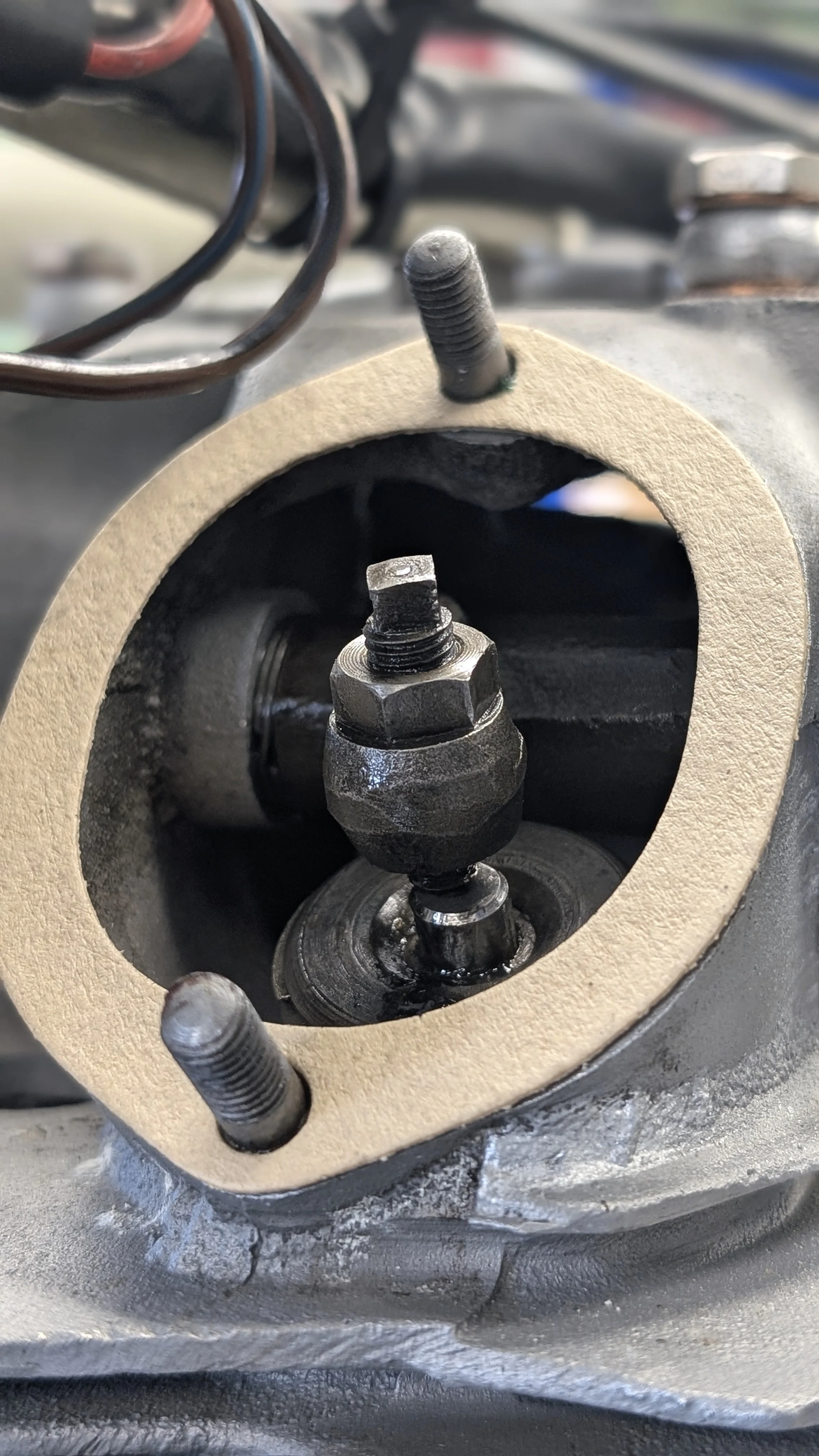 Close-up of engine valve components with valve stem and spring inside a cylinder head, showing part of the engine's internal structure.
