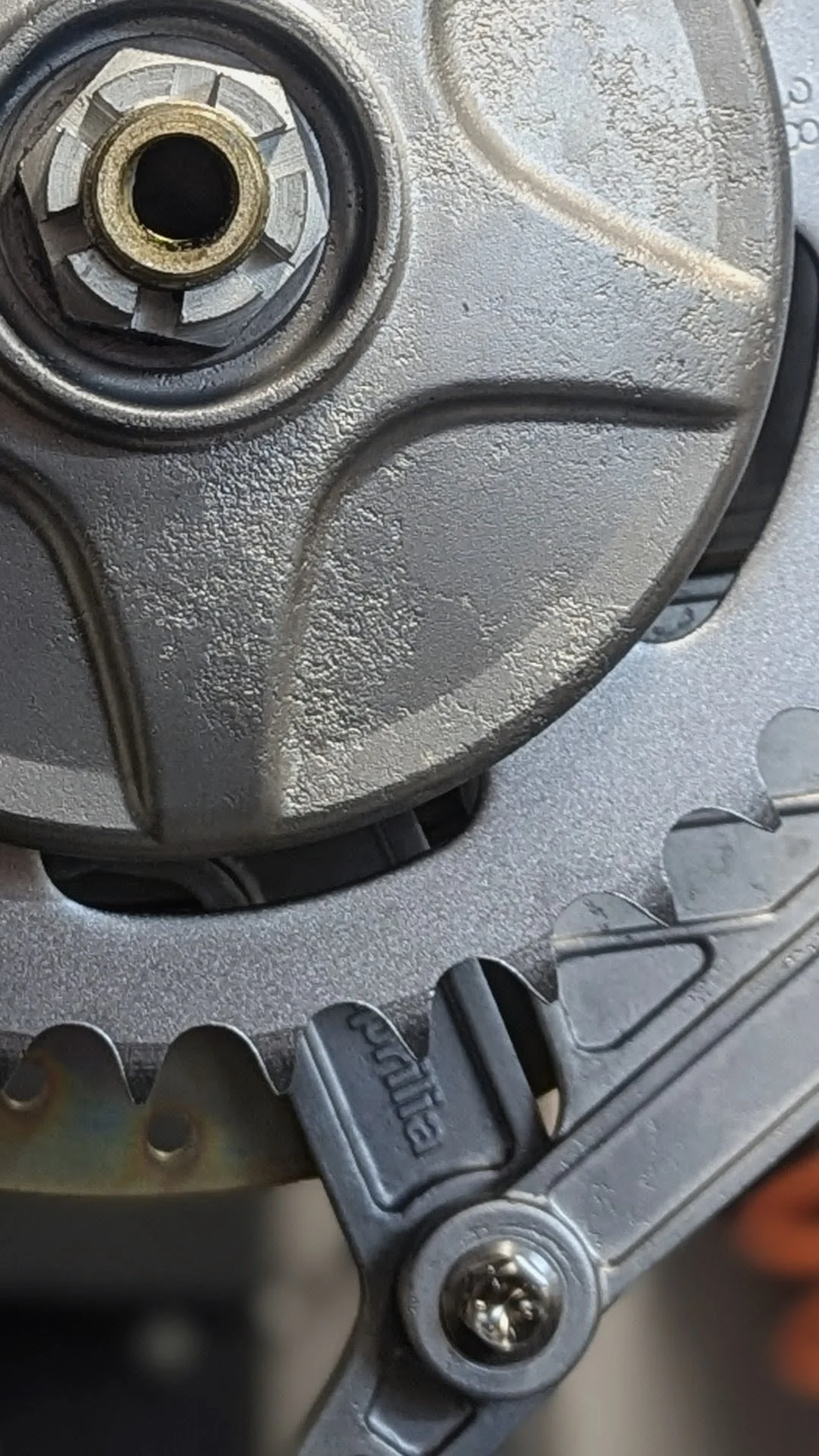 Close-up of a metallic mechanical part with a clock-like gear and a smaller component labeled 'Bionie' in a machine or engine.
