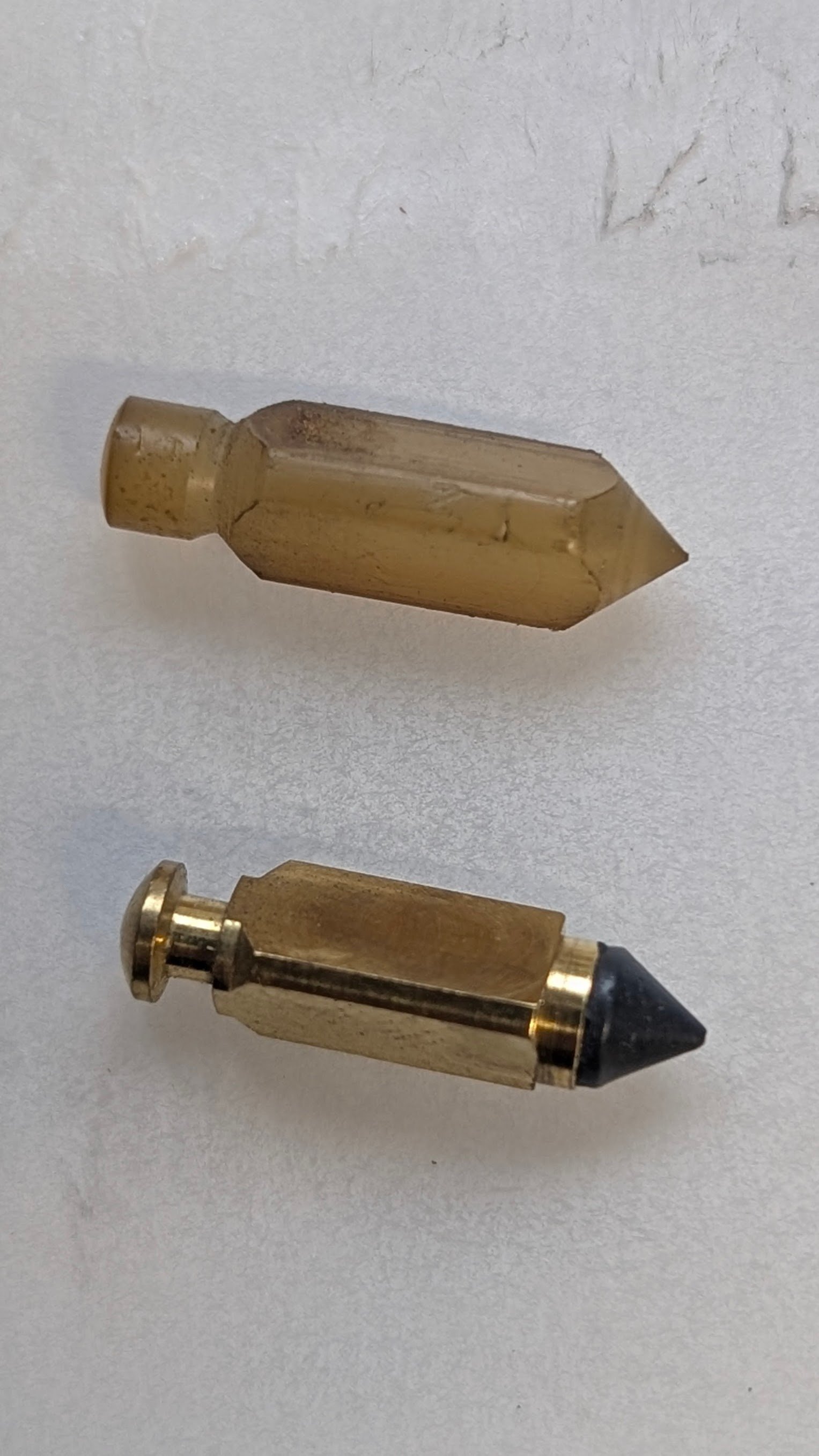 Close-up image of two vintage audio connectors on a white background, one with a gold-colored body and black tip, the other with a gold-colored body and a cream-colored tip.