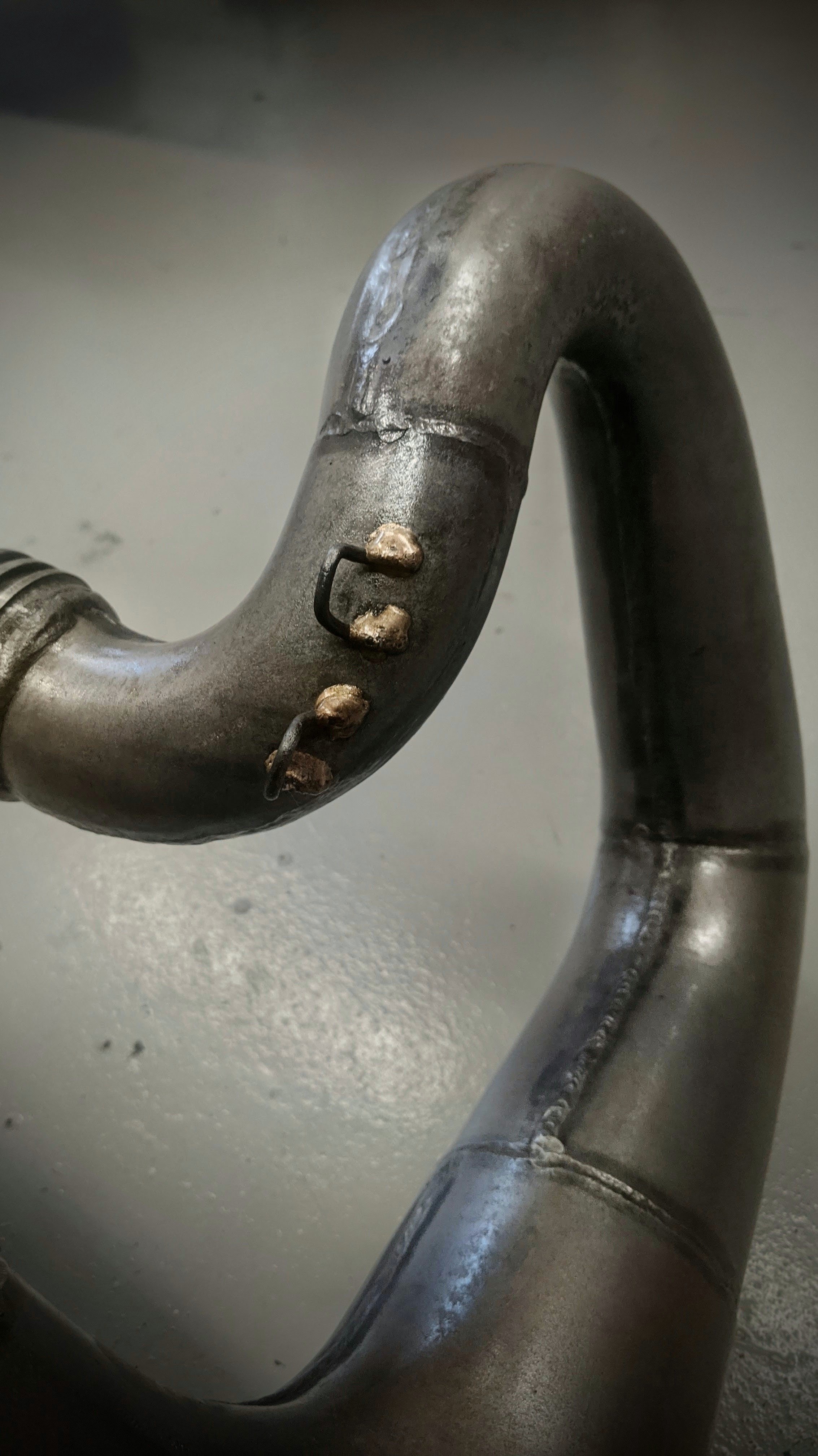 Close-up of a metallic hook with visible wear and rust spots, attached to a metallic surface.