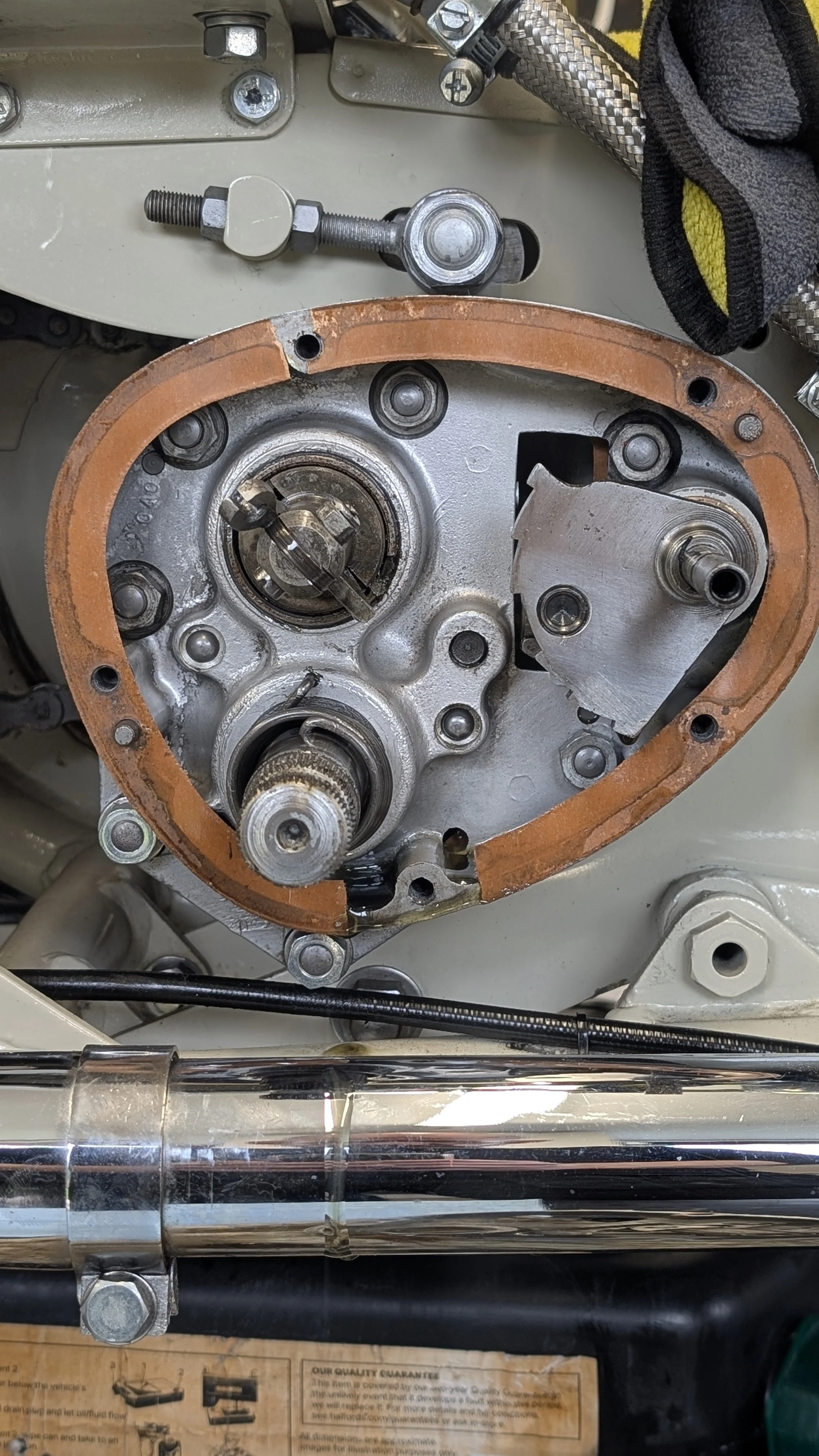 Close-up of a disassembled engine component with visible gears, bolts, and a copper gasket in a mechanical setting.
