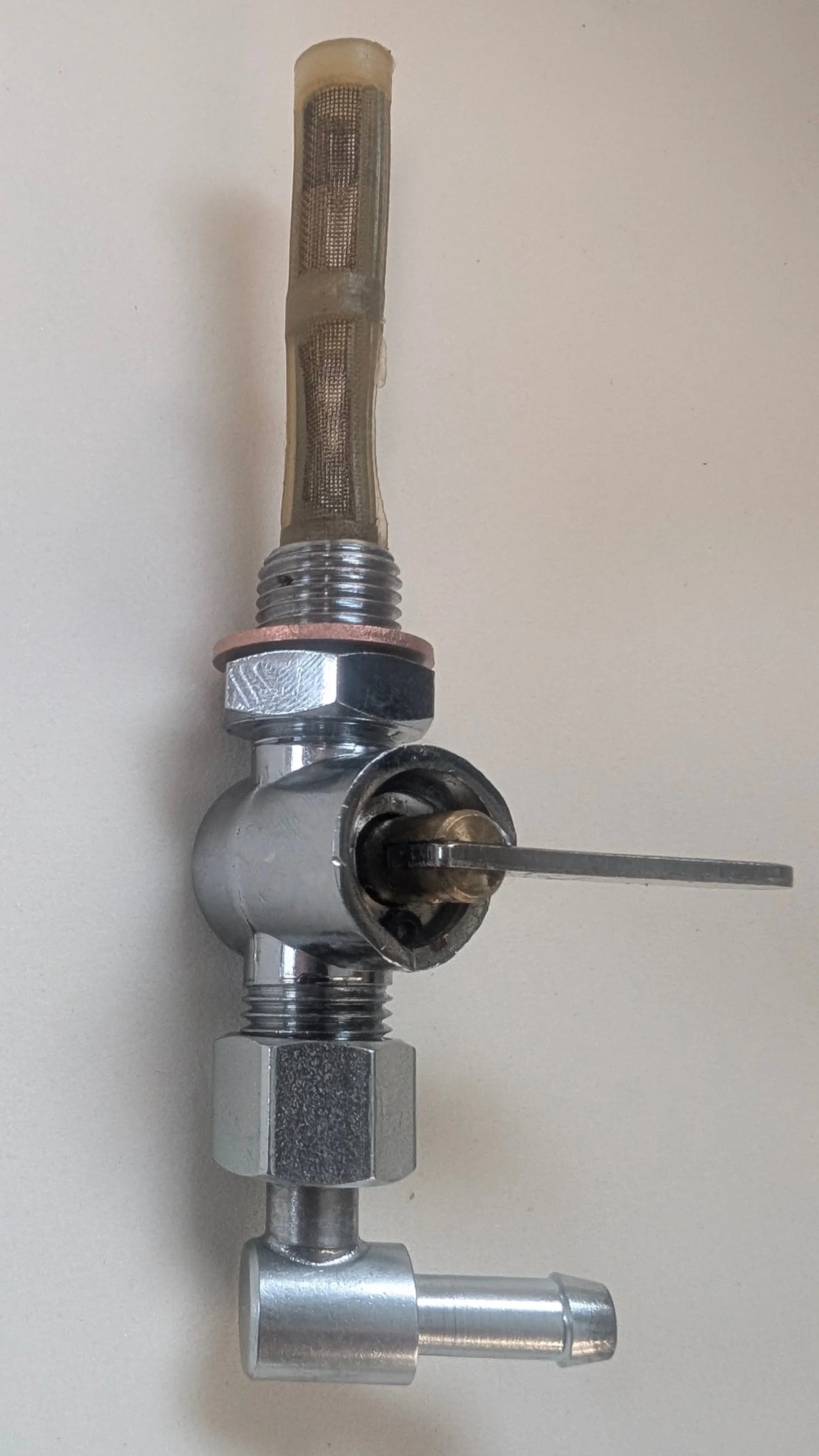 A metal pipe fitting assembly with a mesh filter, threaded connection, and a lever handle on a light-colored surface.