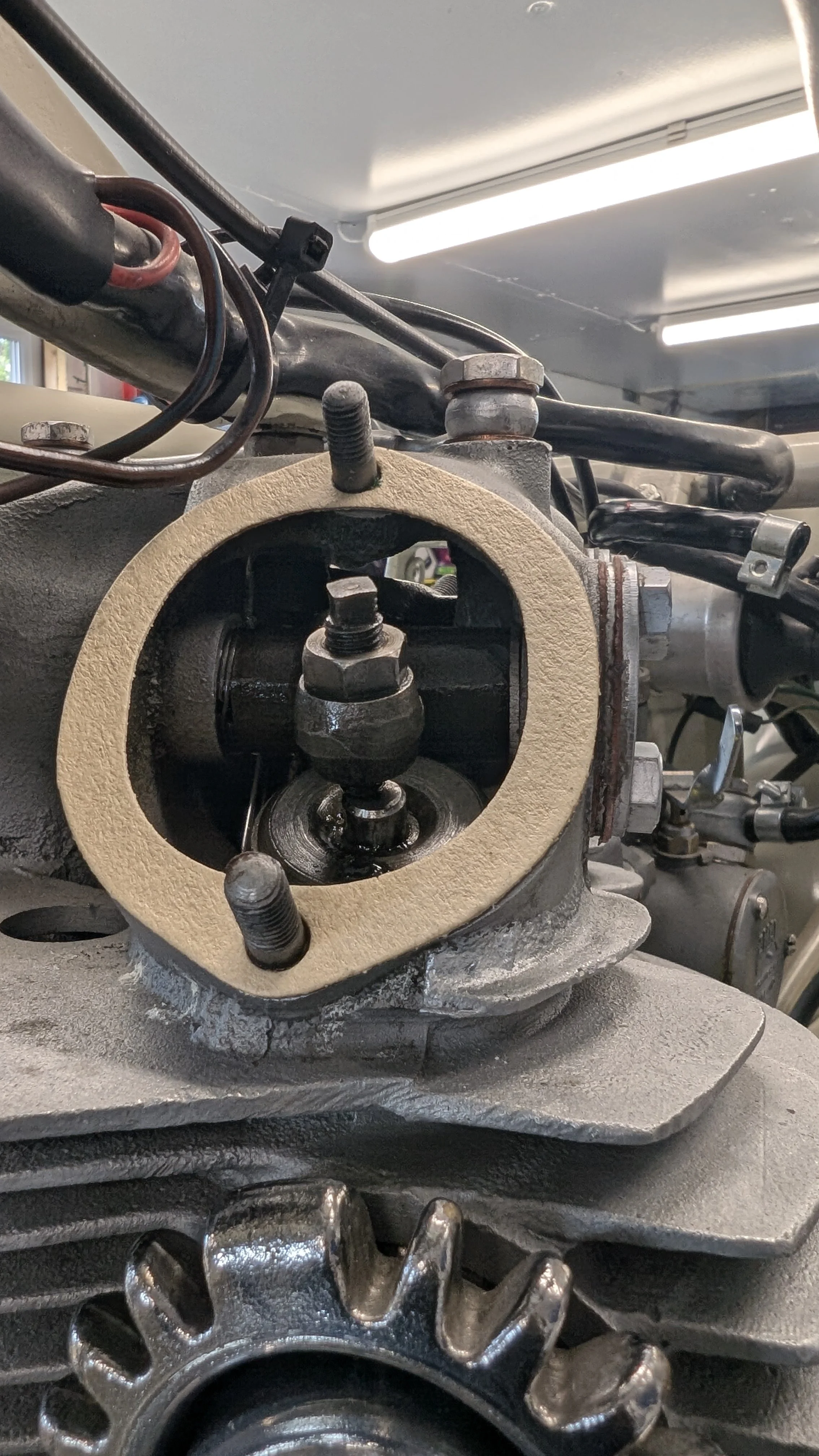 Close-up of an engine component with a partially disassembled cylinder head and visible cam gears, wrenches, and engine parts.