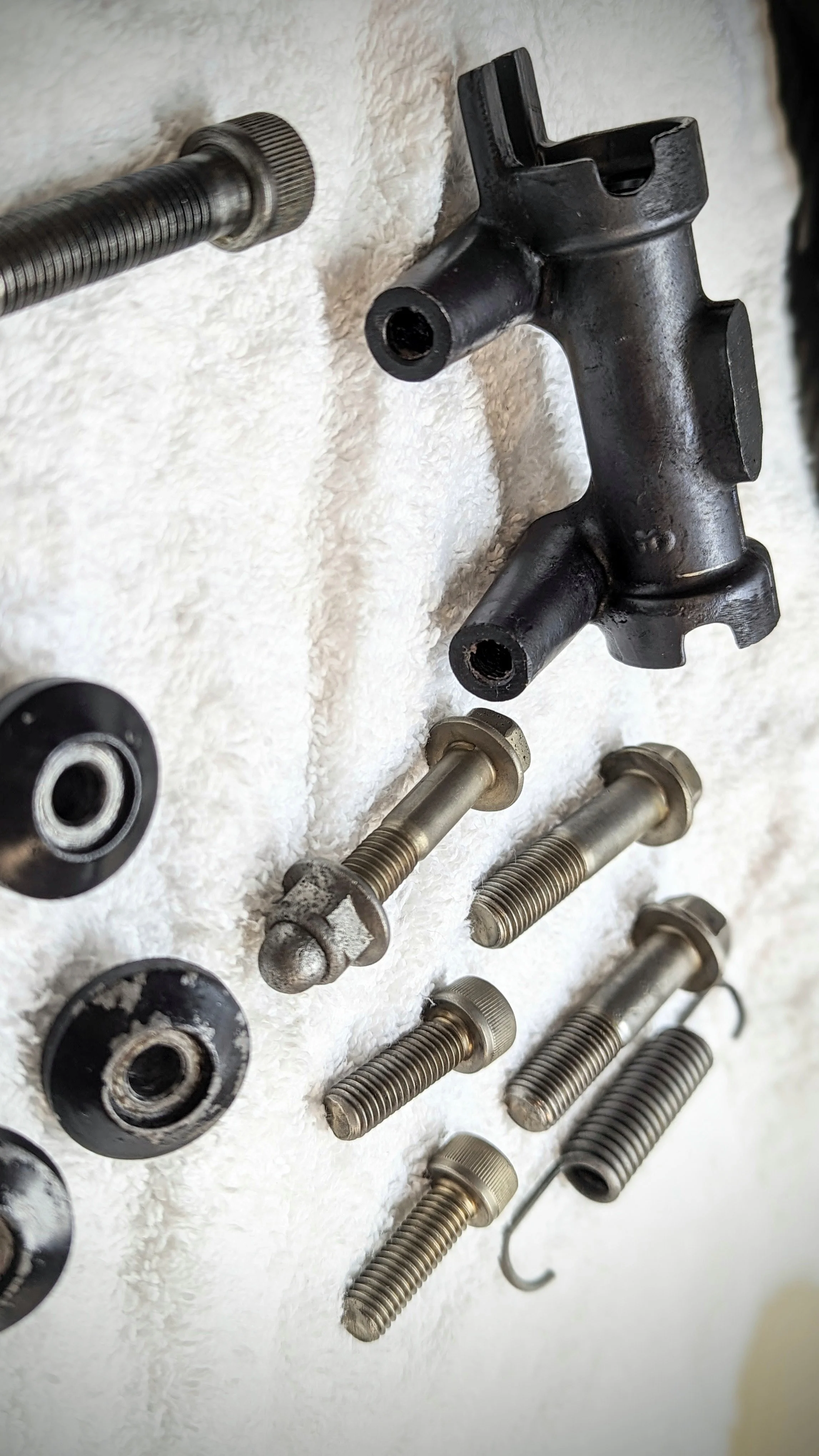 Various disassembled mechanical parts, including bolts, washers, and metal components, laid out on a white surface.