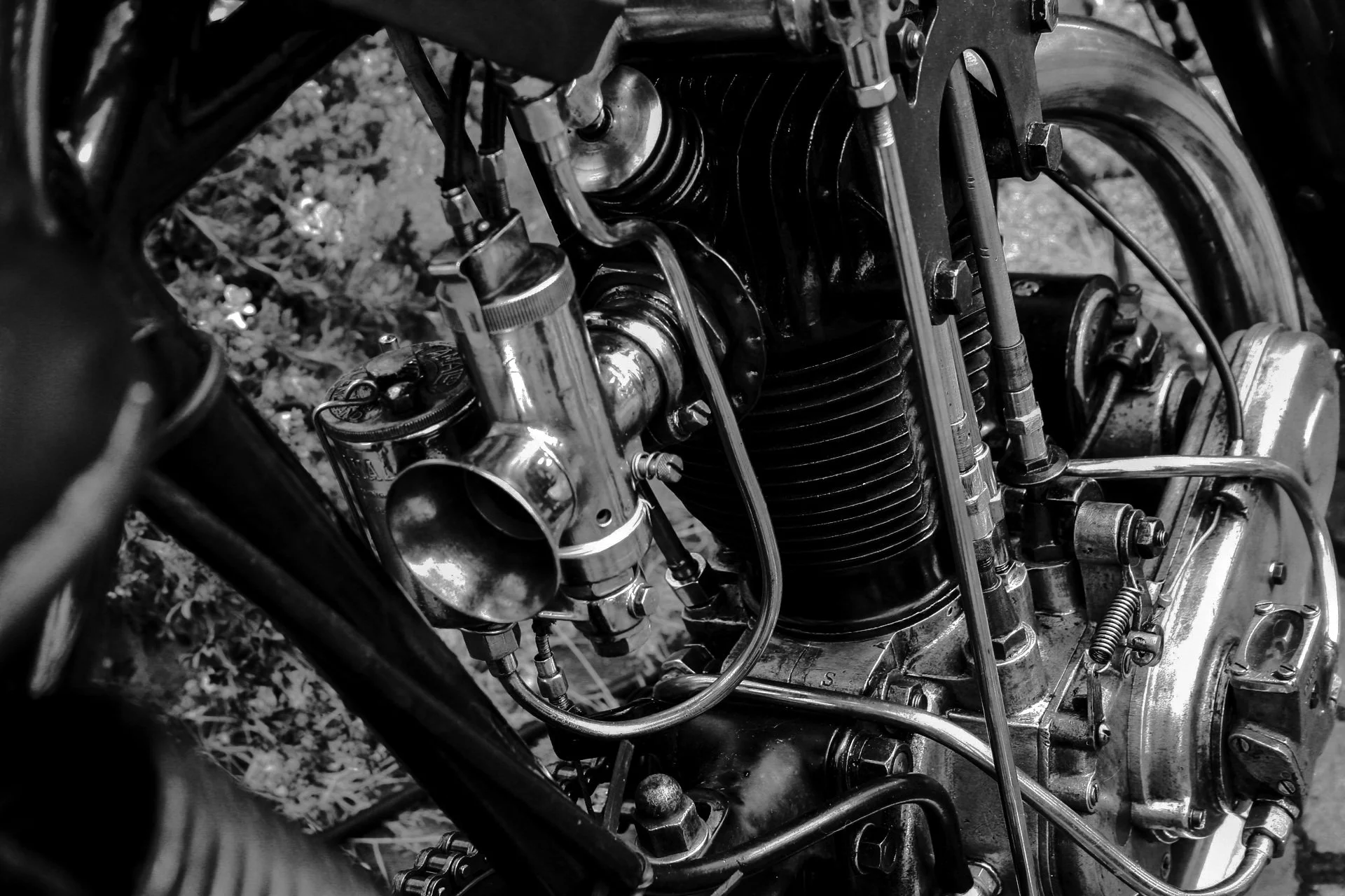 Close-up of a motorcycle engine with various metal components, wires, and cooling fins, in black and white.