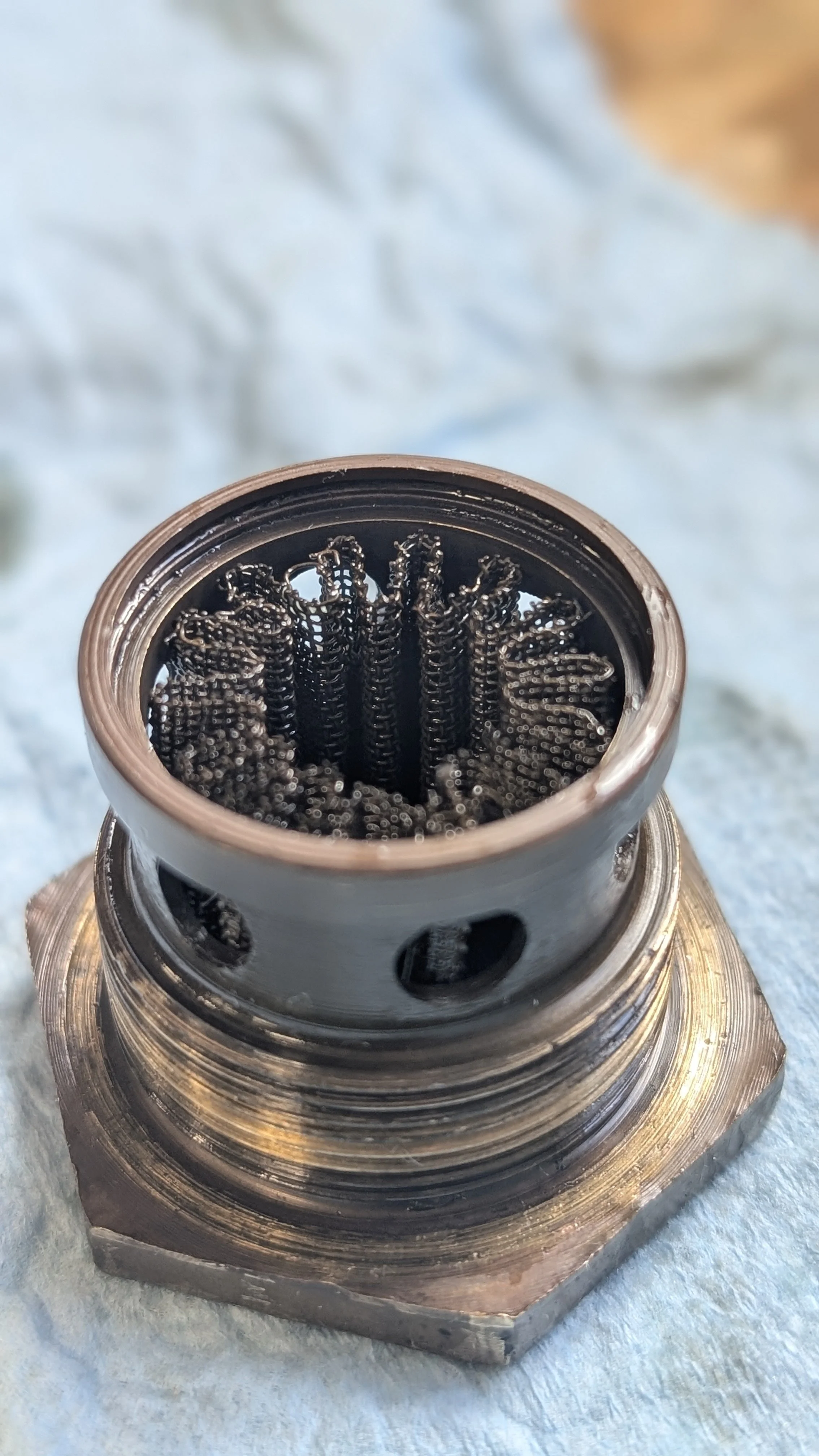A close-up of a spark plug showing its metal threaded base and the black insulator with internal metal components.