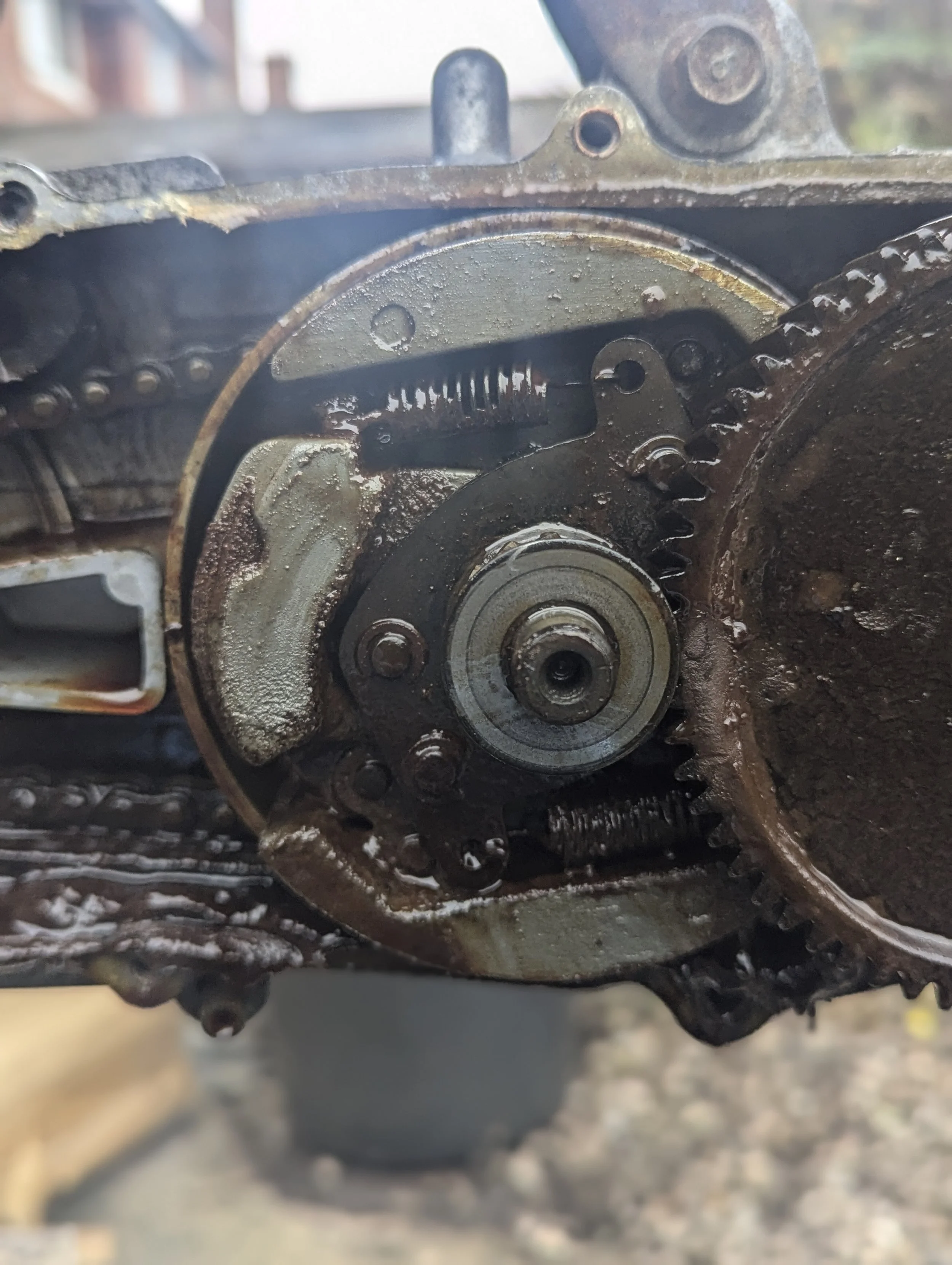 Close-up of a rusty mechanical gear and chain system, part of a machine or engine.
