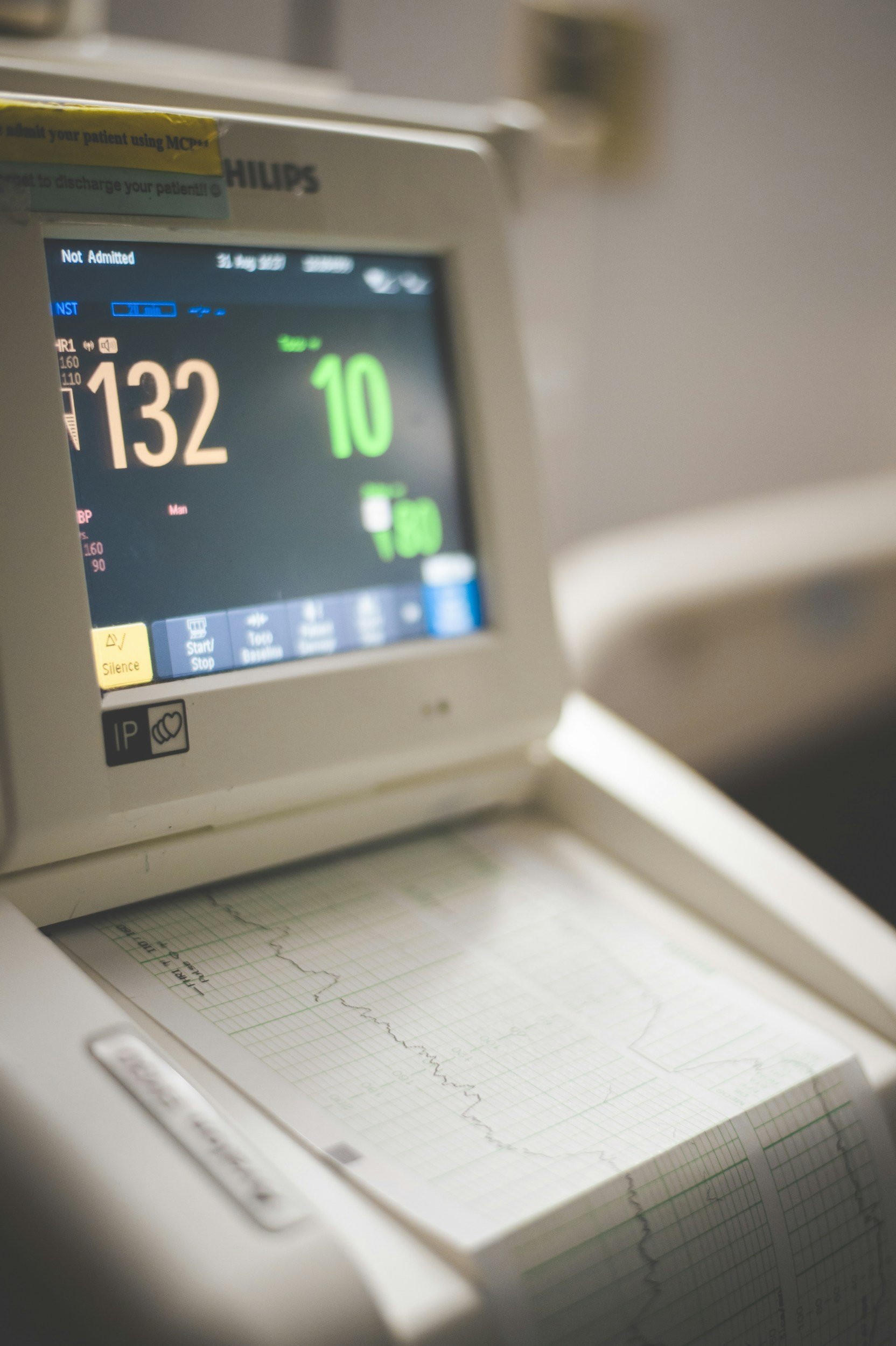 Medical monitor displaying a heart rate of 132 beats per minute and a rhythm of 10, with an electrocardiogram printout showing a heartbeat trace.