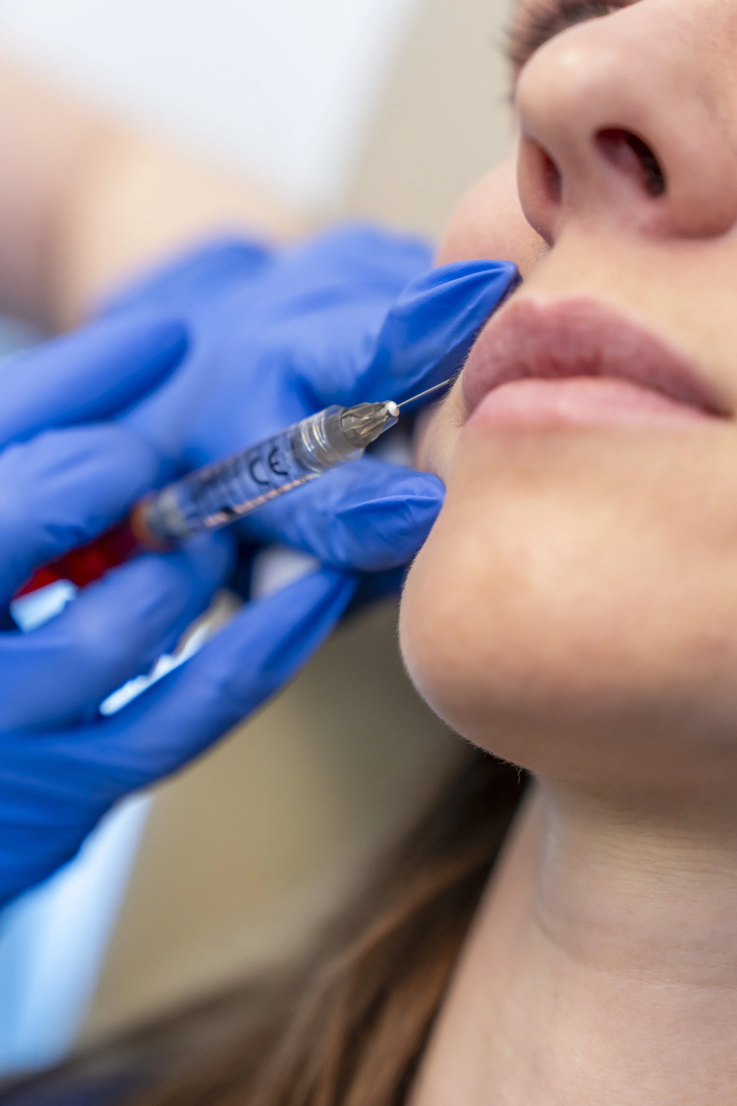 Close-up of a person receiving a vaccination with a syringe from a healthcare worker wearing blue gloves.