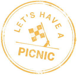 A circular badge with a black background and gold border, featuring a flag on a pole and the words 'Let's Have a Picnic' around the top, with 'PICNIC' at the bottom.