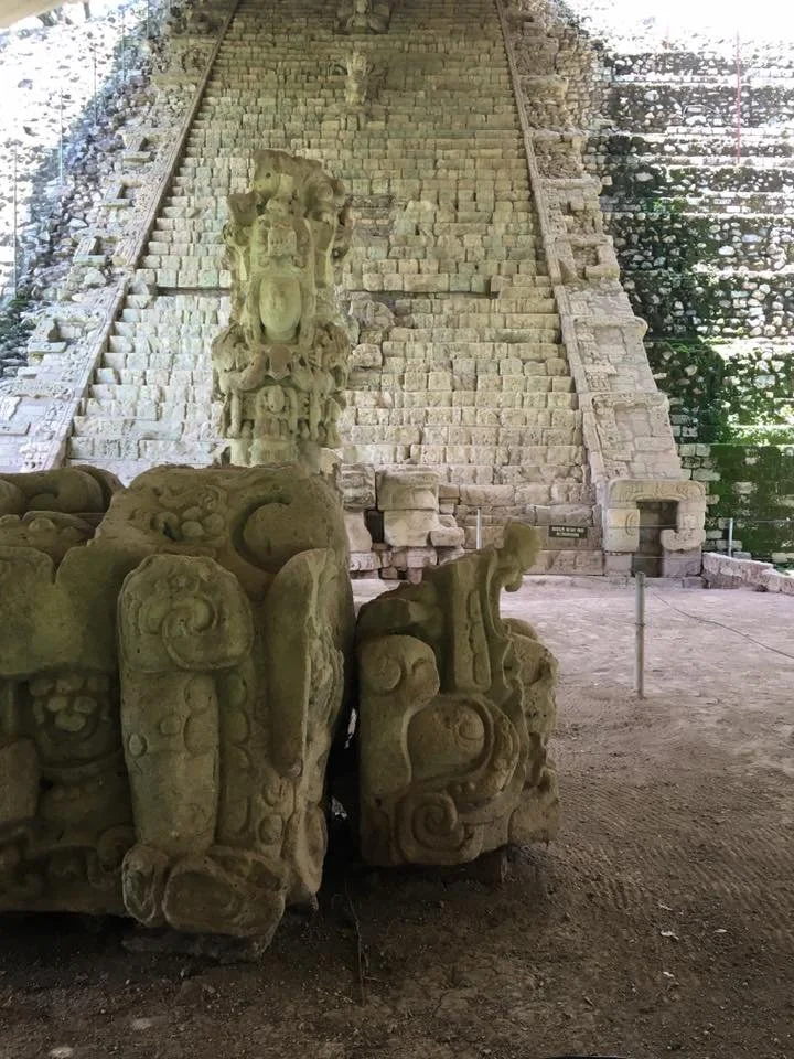 Ancient pyramid and carved stone sculptures at an archaeological site.