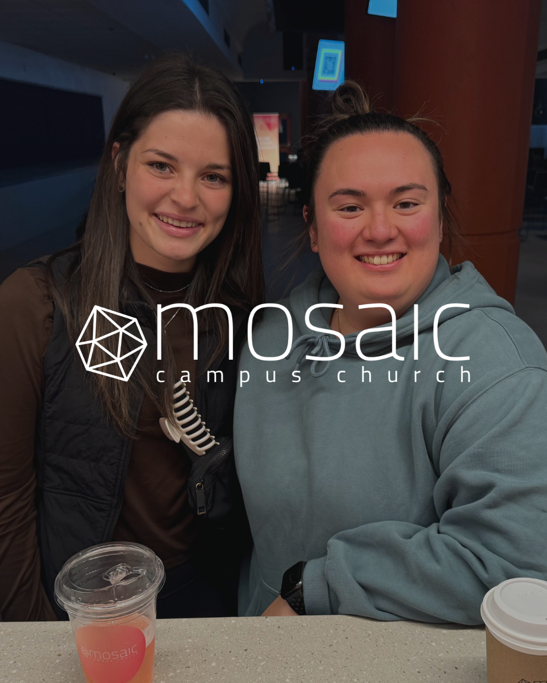 Two young women smiling at a cafe counter, with a Mosaic Church logo overlay on the photo.