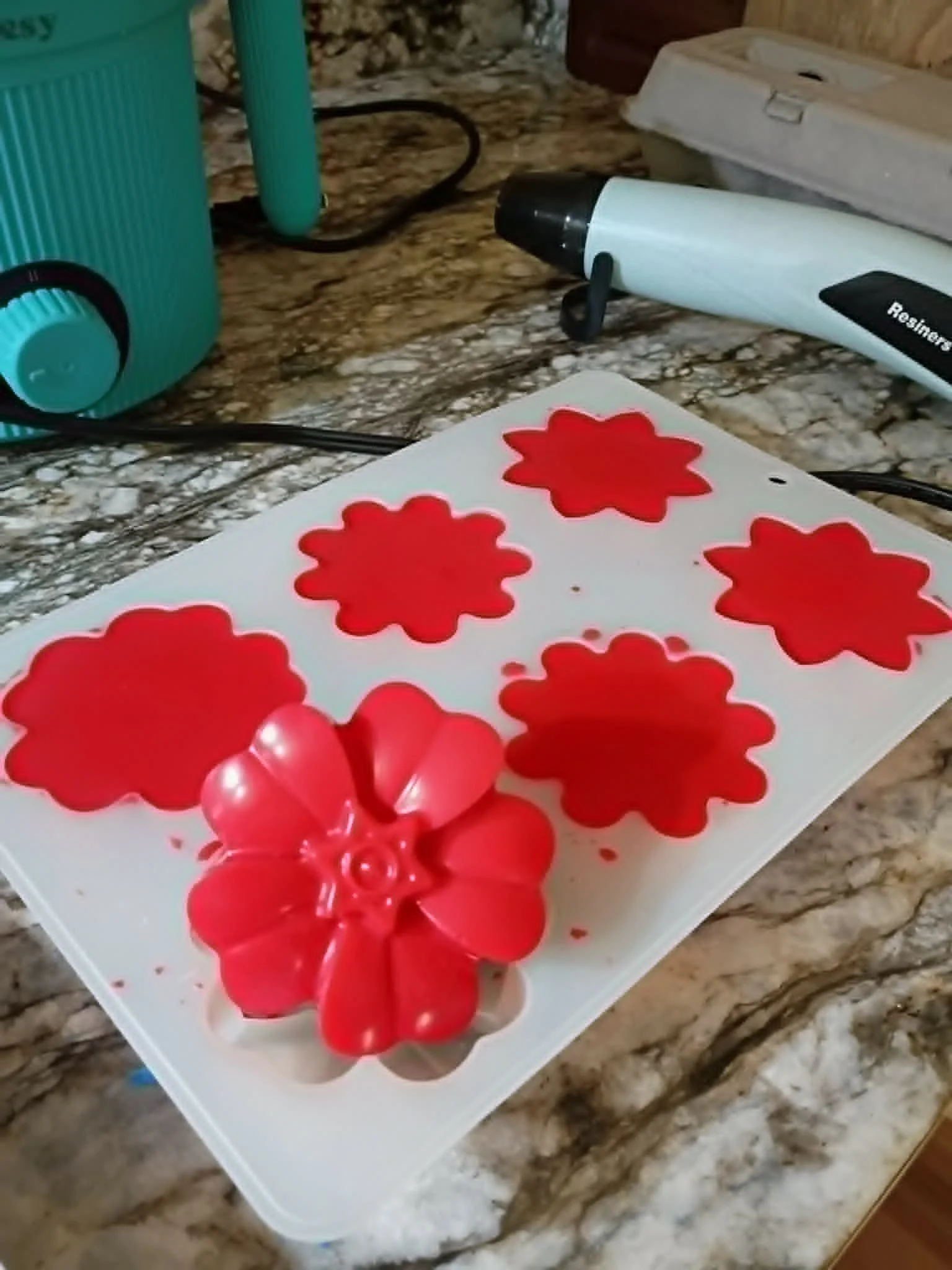 Red flower-shaped cookie cutters and a red flower-shaped object on a white tray.