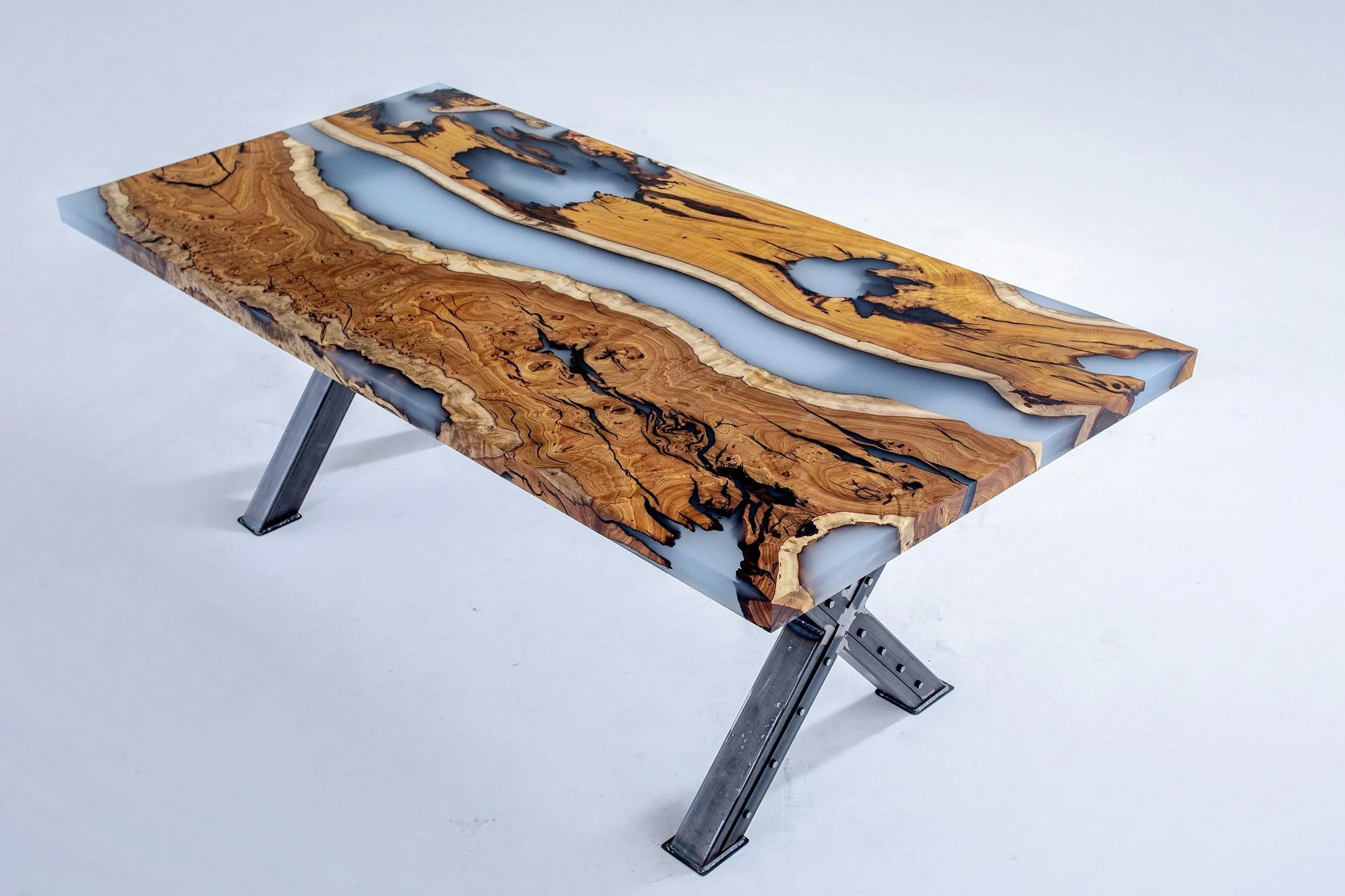 A rectangular table with a wooden top featuring natural burl wood patterns and resin inlays, supported by metal folding legs.
