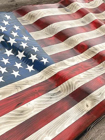 Close-up of a wooden American flag with red and white stripes and a blue field with white stars.