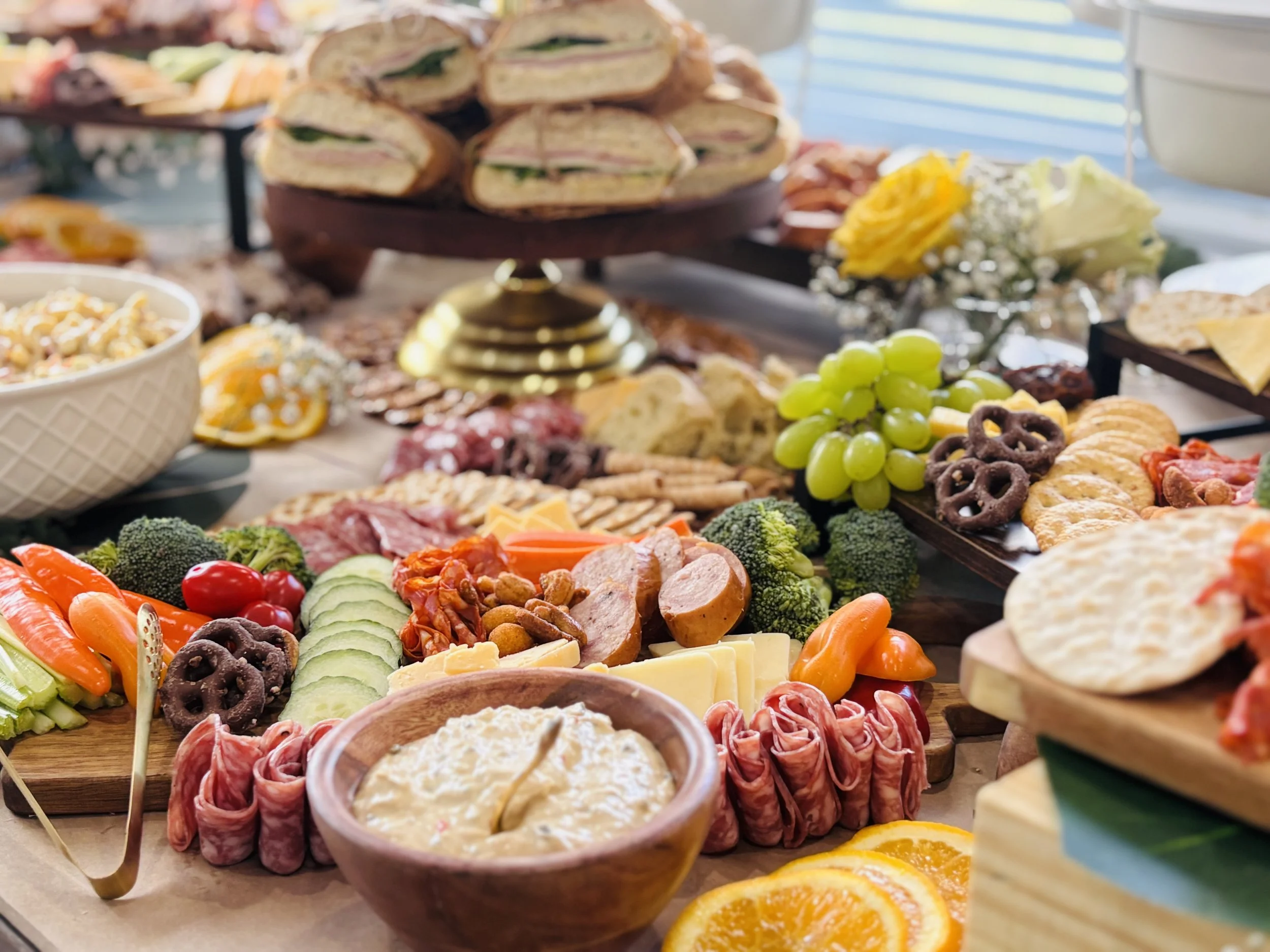 Luxury charcuterie grazing table by Highly Flavored Catering featuring gourmet meats, cheeses, fresh vegetables, sandwiches, crackers, fruit, and appetizers beautifully displayed for a wedding, corporate event, or private celebration.