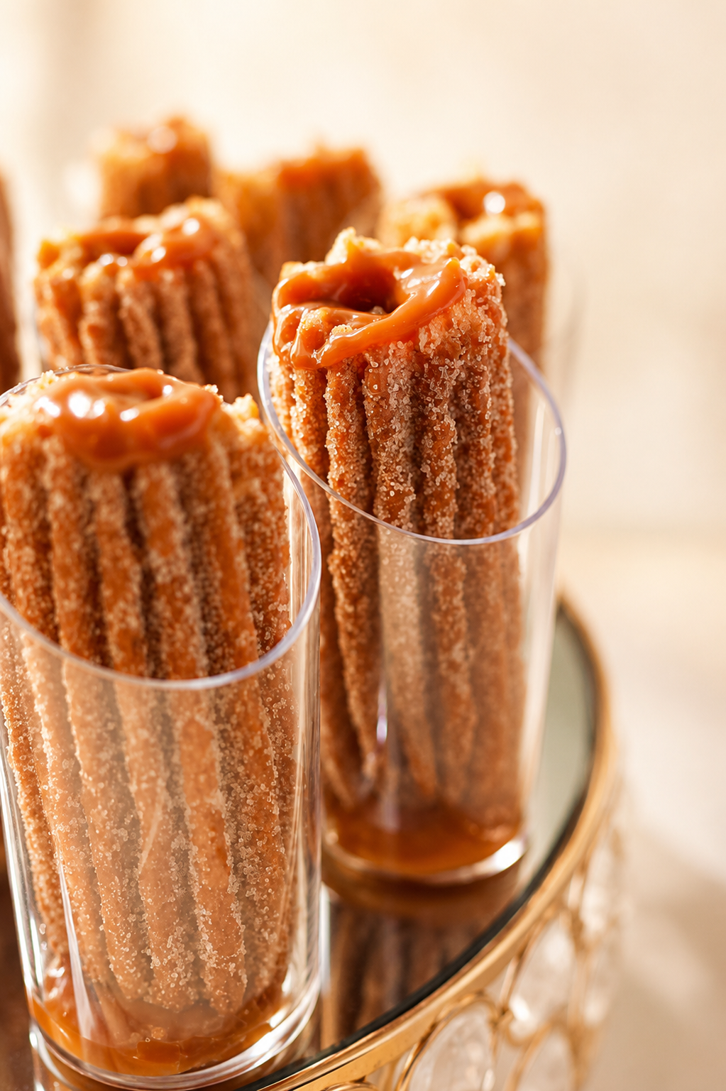 “Elegant churro shooters with cinnamon sugar and caramel drizzle, beautifully displayed in clear dessert cups for a luxury catering dessert table by Highly Flavored Catering.”