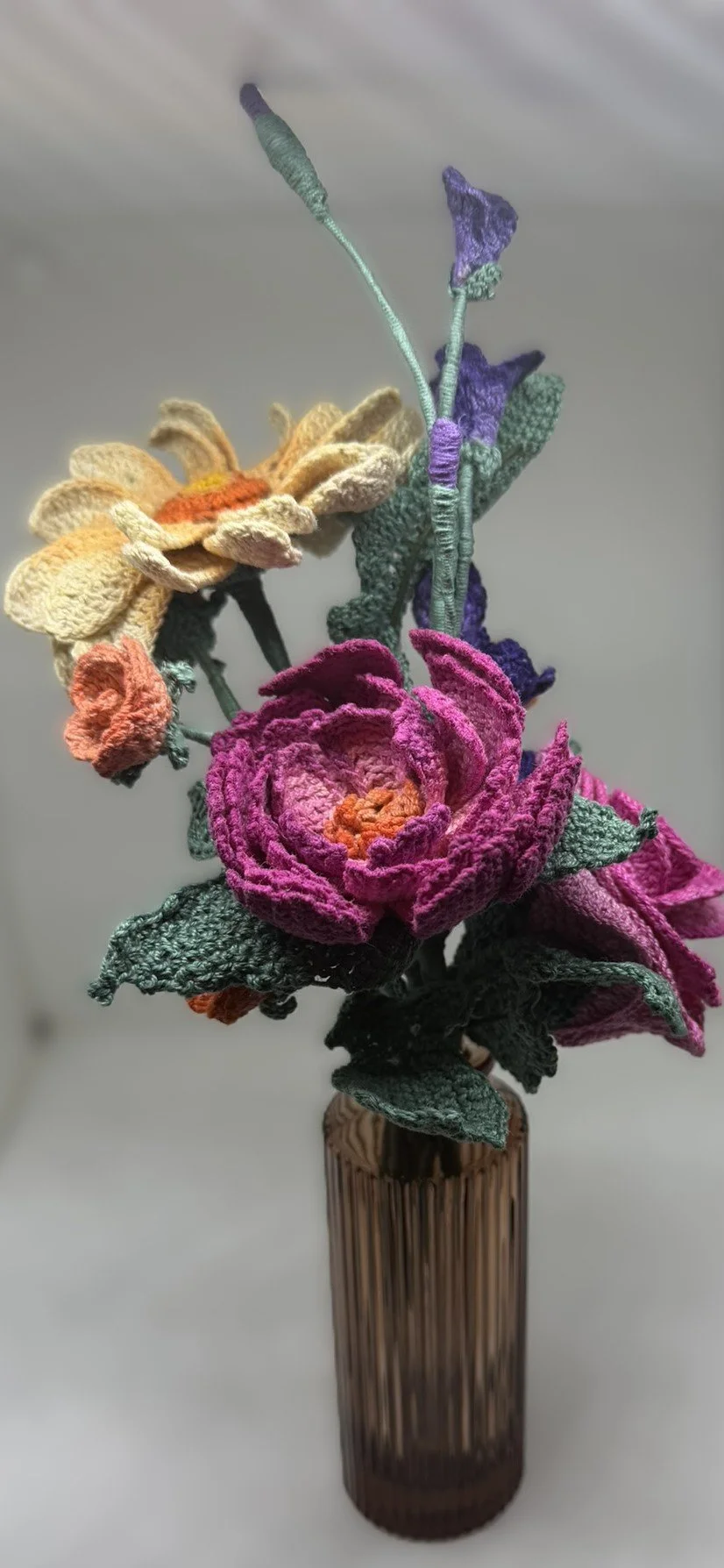 Colorful embroidered flower bouquet in a brown striped vase.