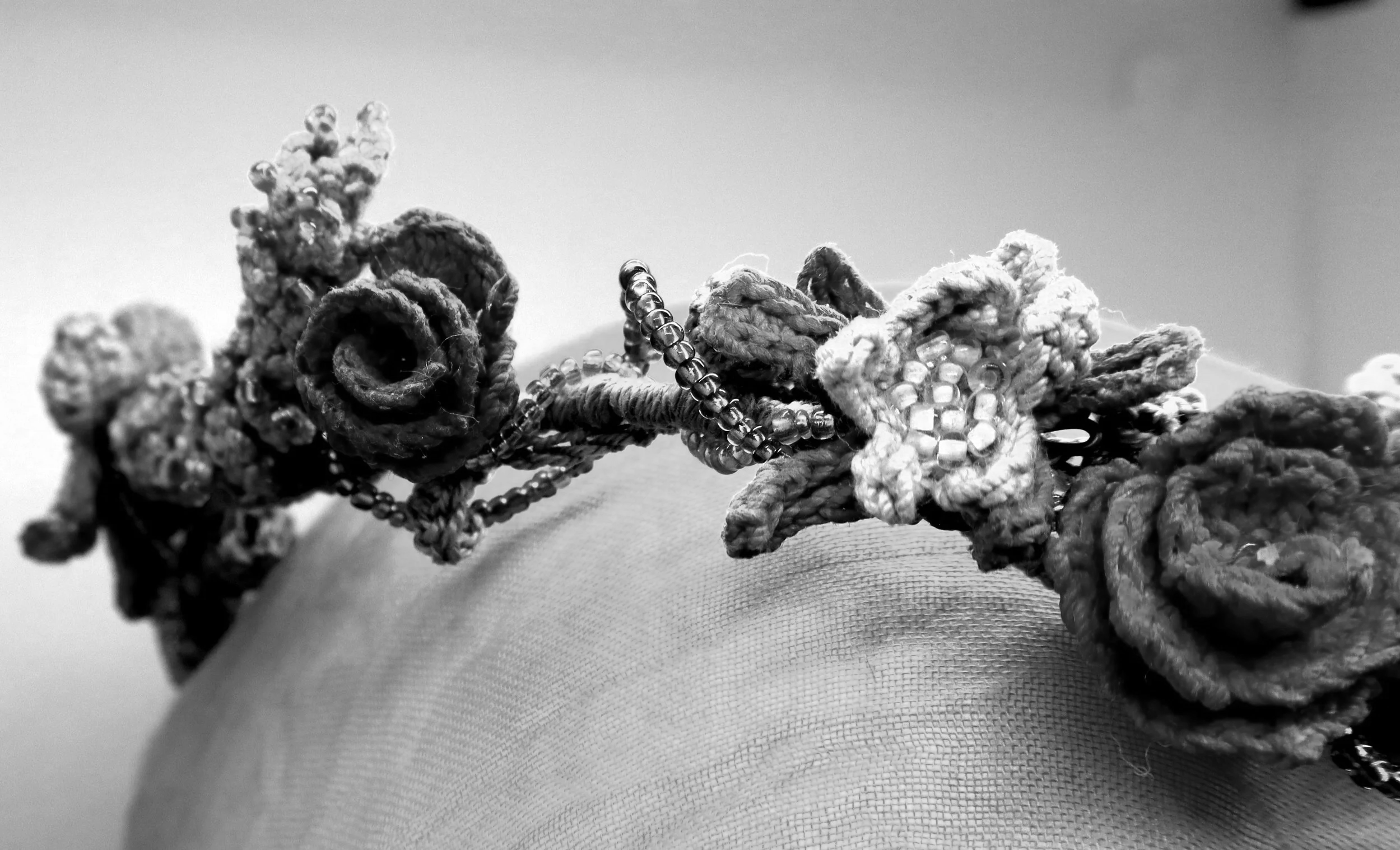 Close-up of a jumbled pile of braided and knotted ropes intertwined with strands of small beads, lying on a fabric surface.