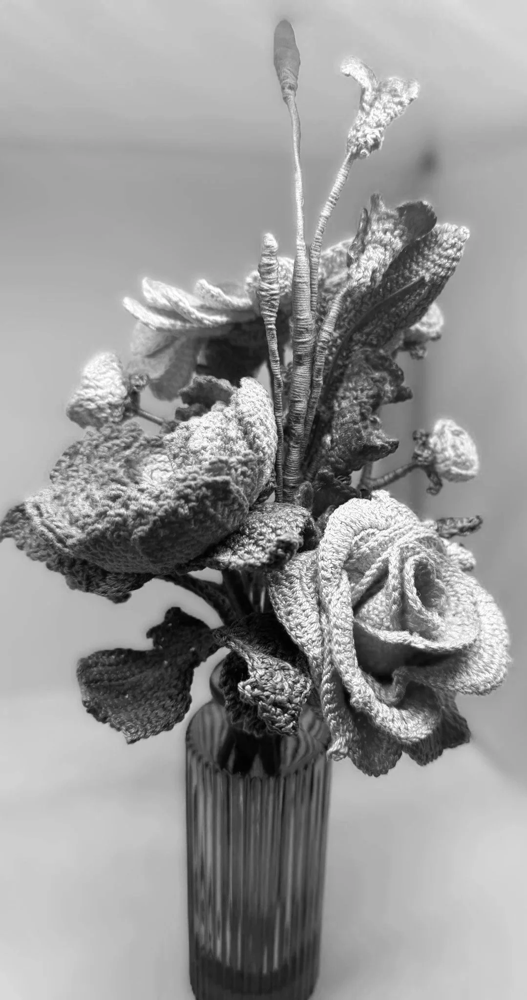 A black and white photo of a bouquet of wilted and dried flowers in a vase.