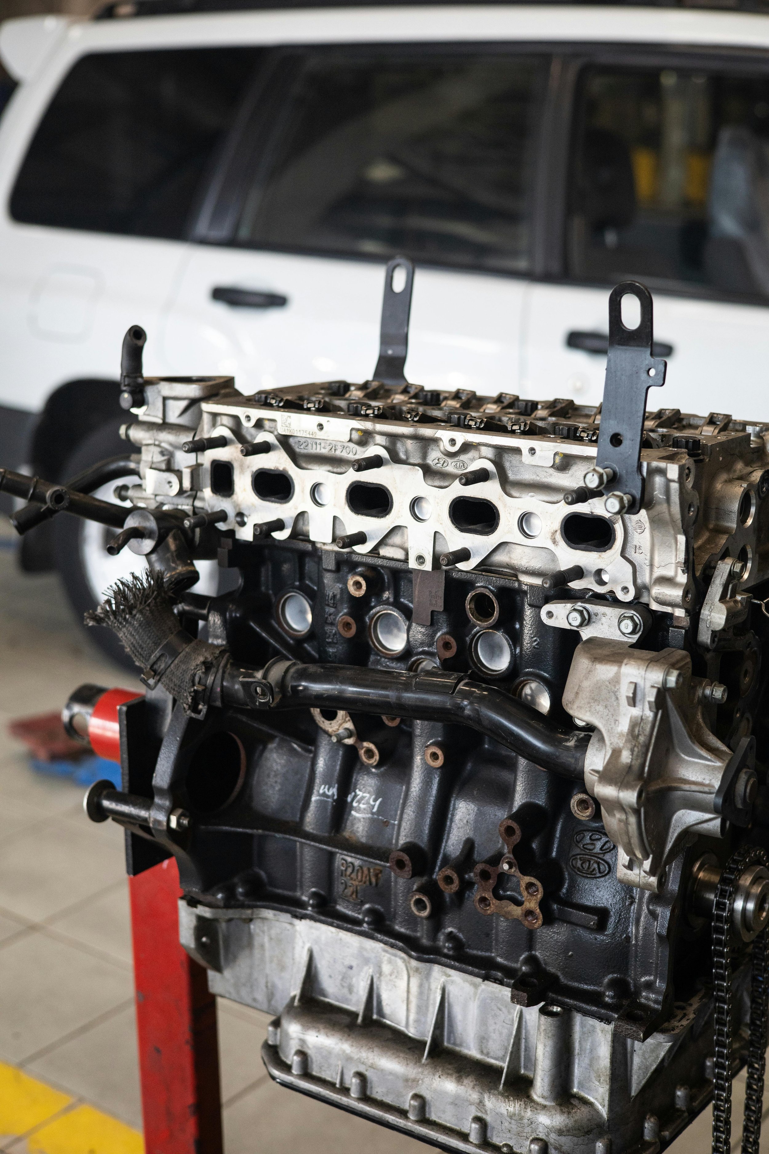 An engine block without the cylinder head installed, placed on a stand in a workshop or garage.