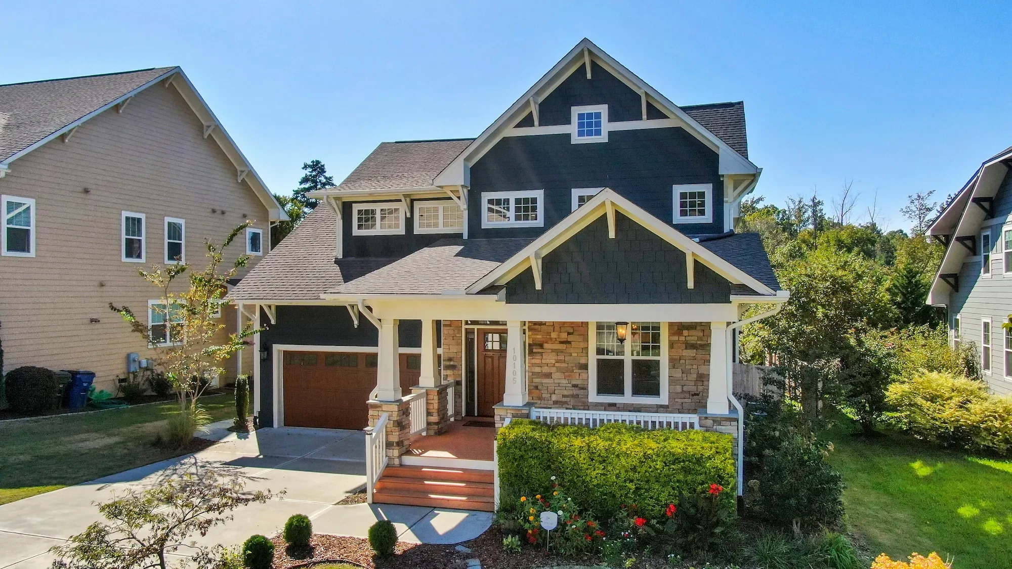 Craftsman home with stone siding and covered front porch — soft wash house washing removes algae and mildew without damage