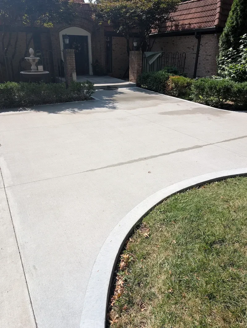 Freshly cleaned concrete driveway with curved edging, showing an even, streak-free result