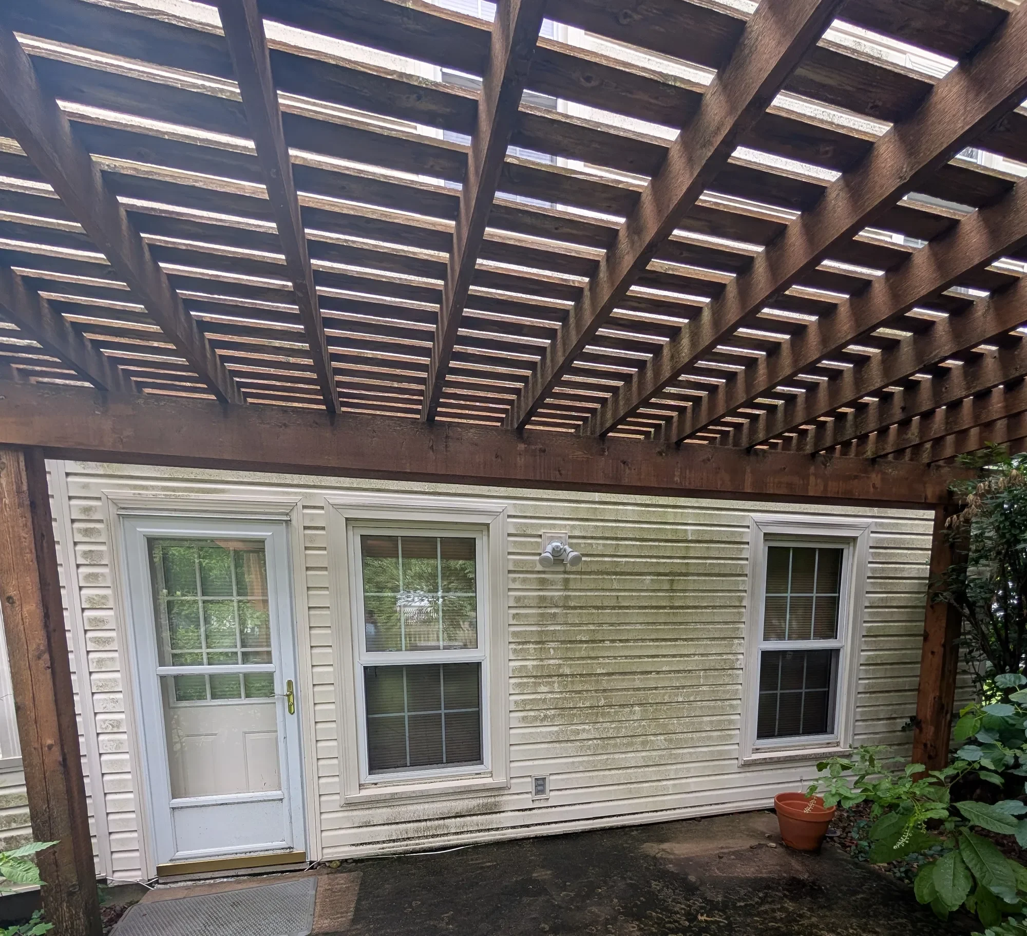 House siding under pergola before soft washing, algae visible — Olathe KS