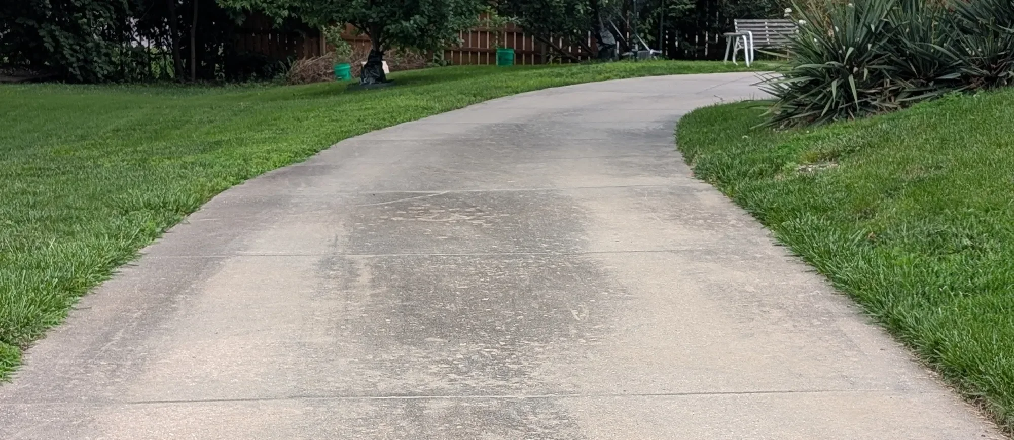 Curved concrete walkway with dark staining before cleaning, Lenexa KS