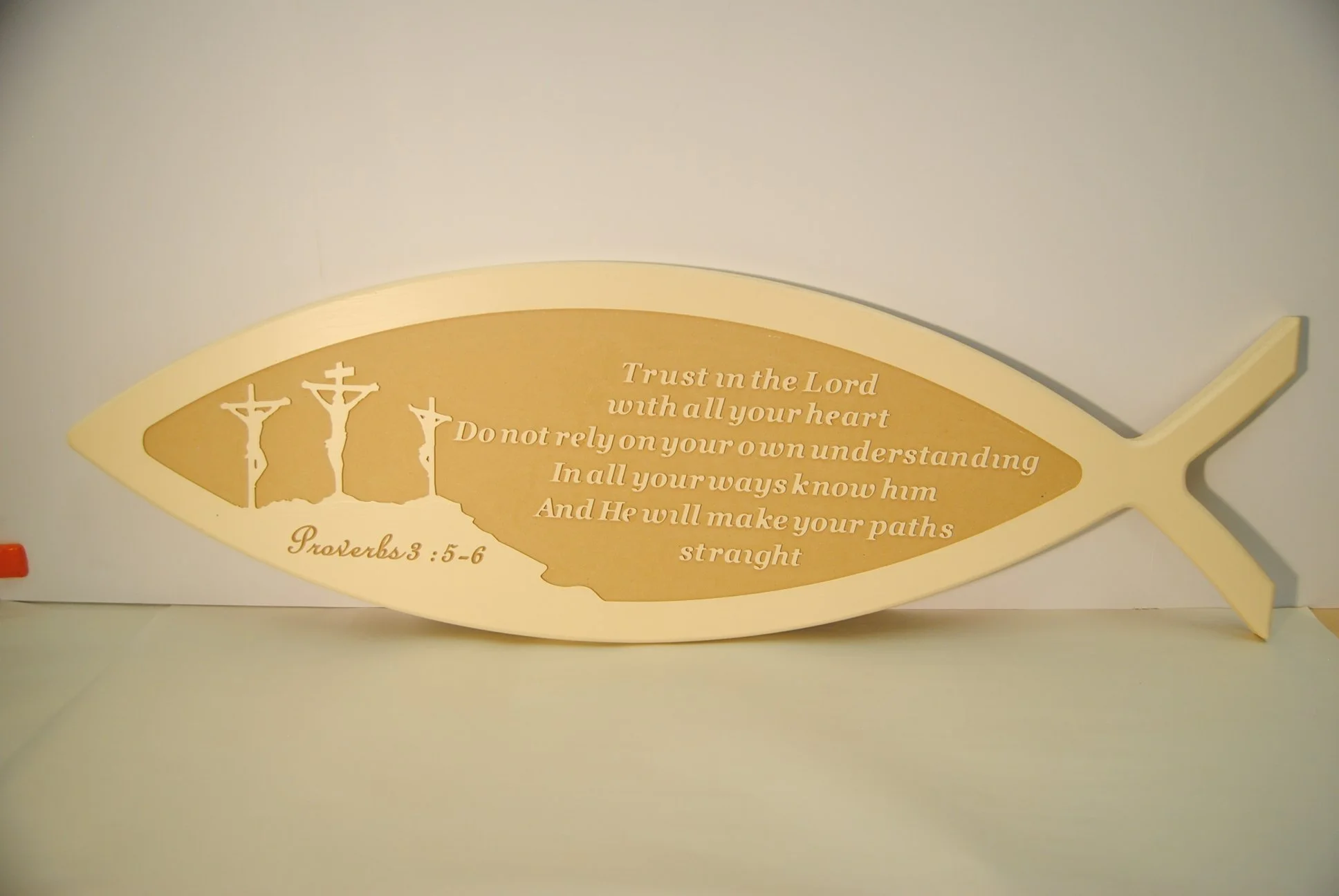 Gold-colored fish-shaped plaque with a Bible verse, Proverbs 3:5-6, about trusting in the Lord and not relying on one's own understanding, with three crosses on the fish's tail.