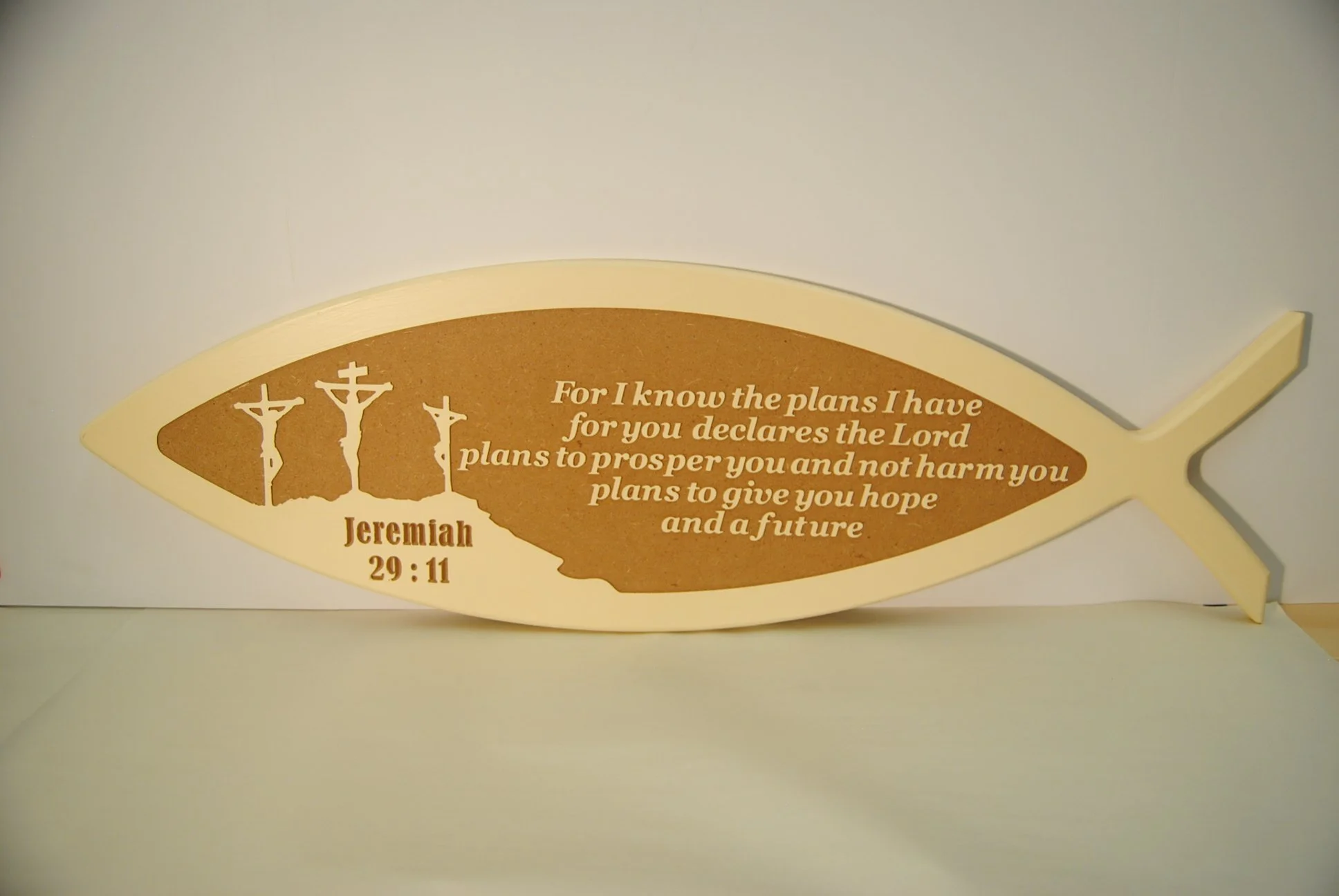 A fish-shaped plaque with a biblical quote and three crucifixes. The quote is from Jeremiah 29:11 and reads, "For I know the plans I have for you declares the Lord plans to prosper you and not harm you plans to give you hope and a future."